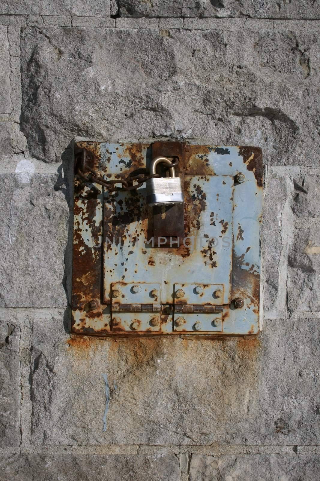 Iron lock and rusty metal on a stone wall.