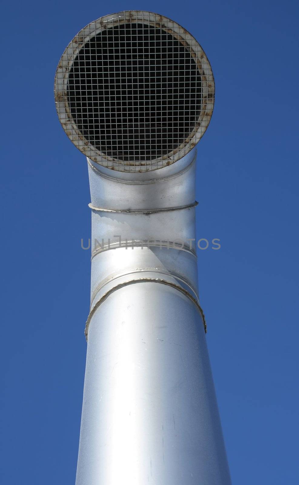 Shiny metallic ventilation pipe with wire mesh on a blue sky background.