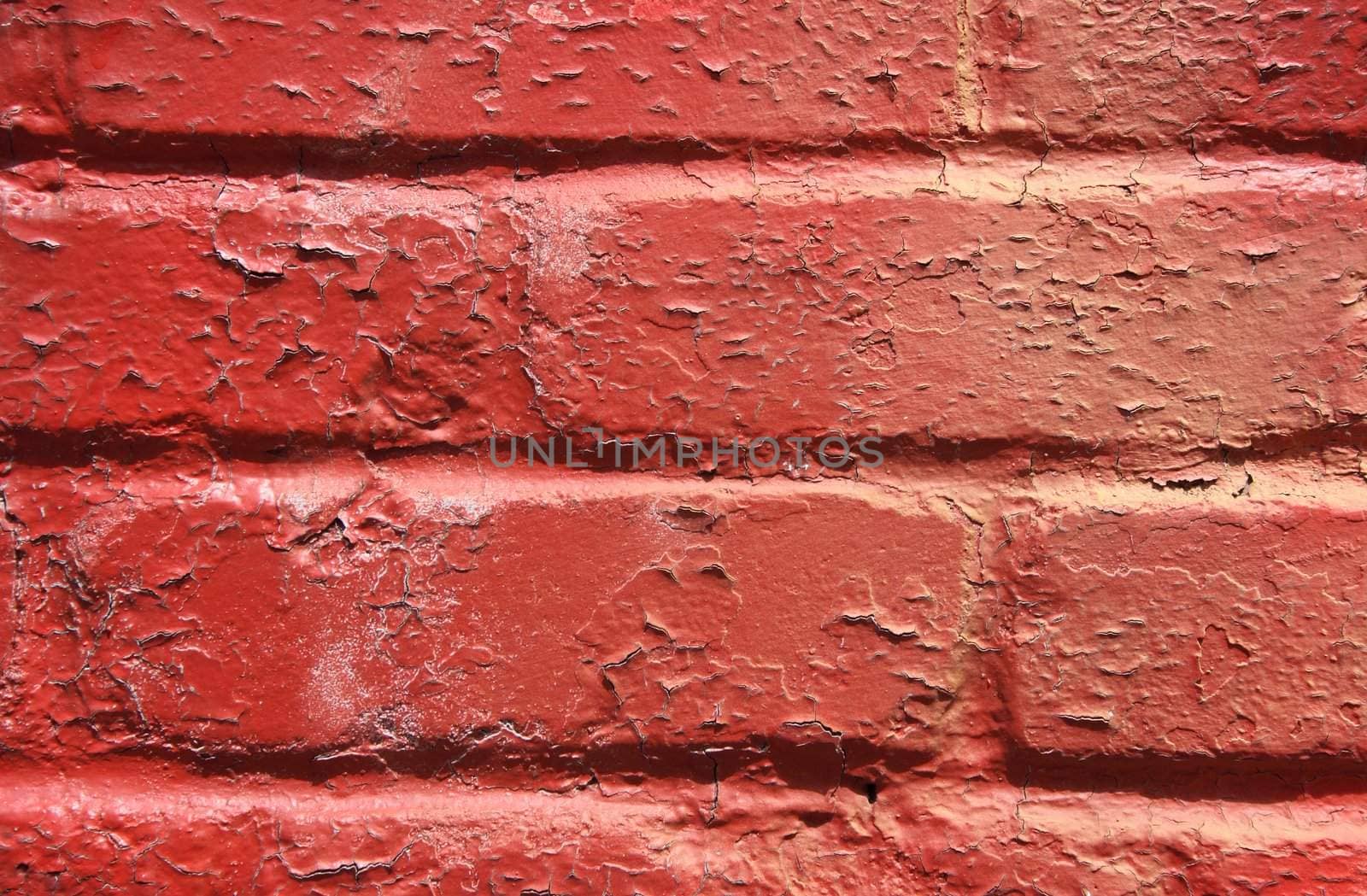 Red peeling paint on an old brick wall.