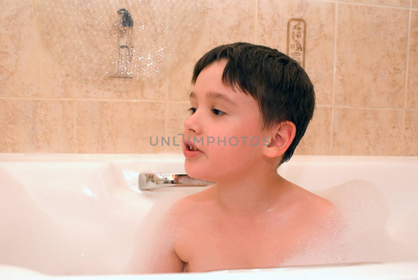 little boy is sitting in bathtun with foam