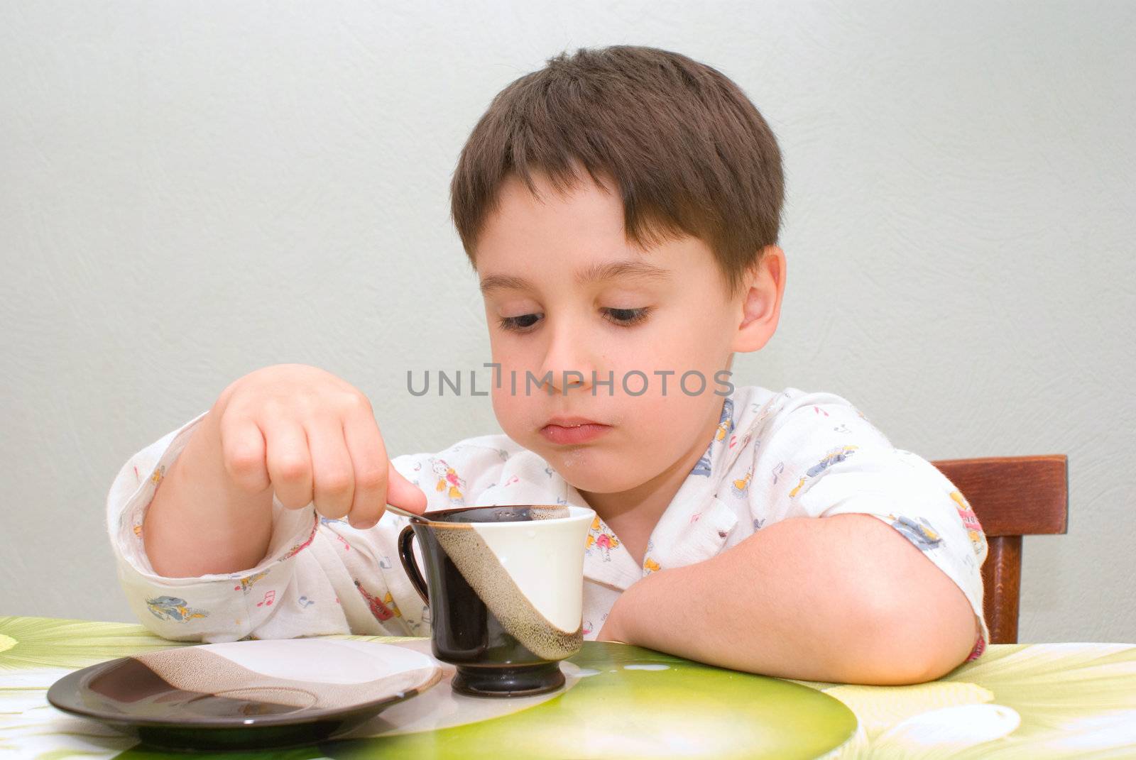 little  boy is having breakfast at the table