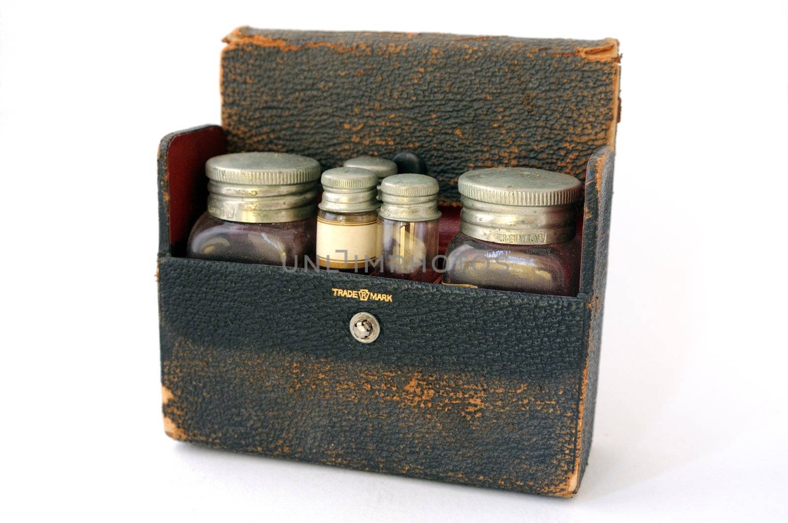 A vintage, distressed leather pharmaceutical case with a red lining, filled with two large bottles and three small vials.  One of the vials has a blank label facing forwards.