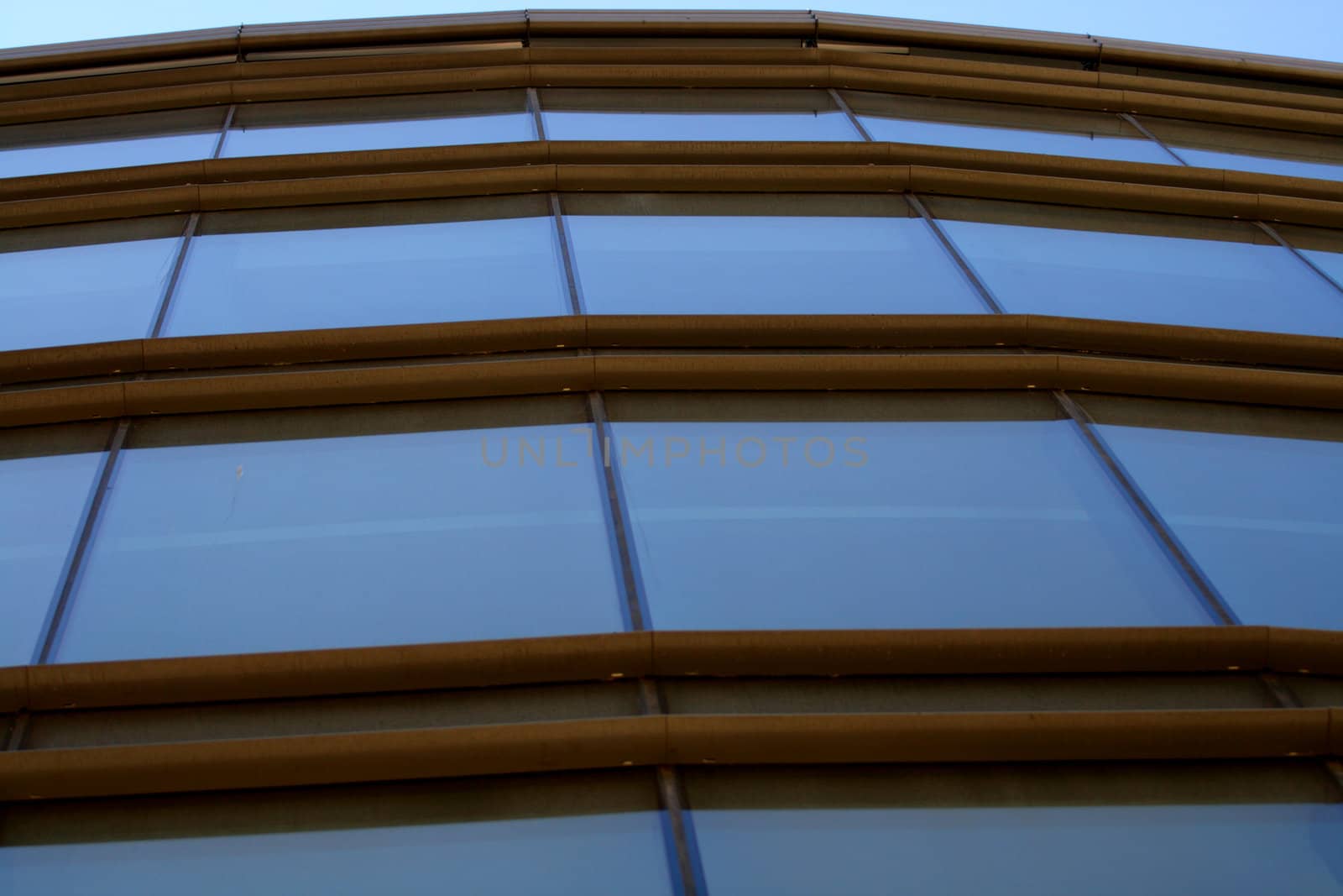 Glassy front reflective blue sky. Metal rusty brown cross supporting construction.
 