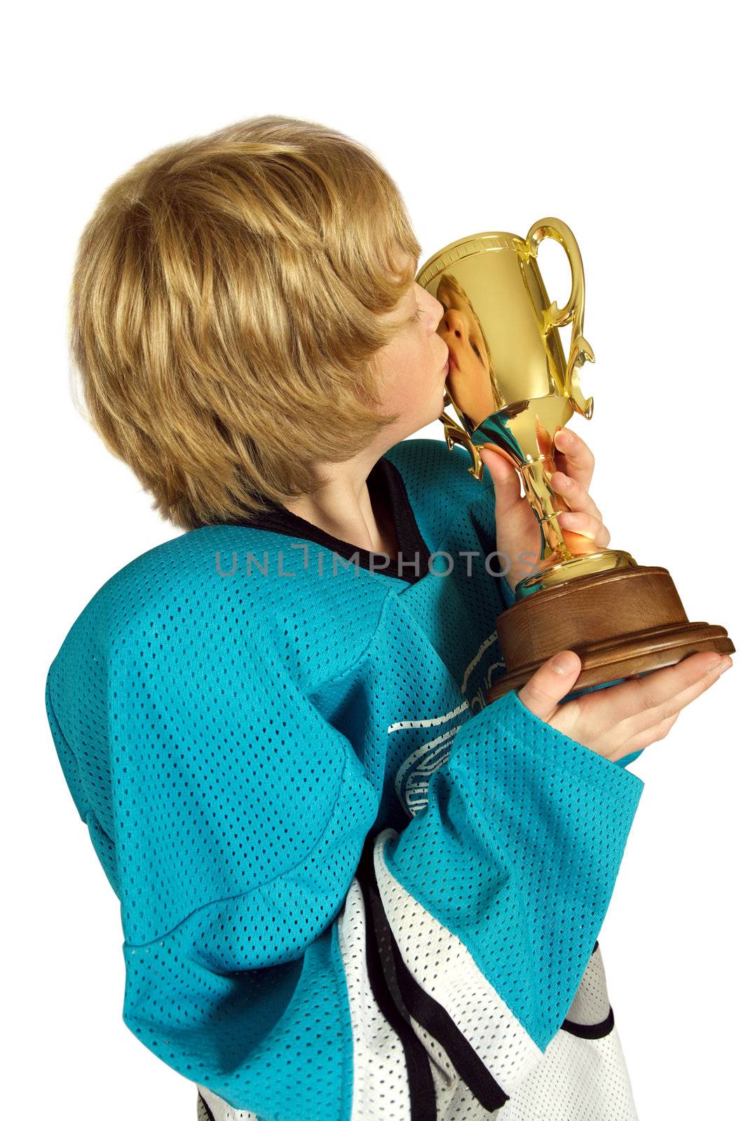 Young boy athlete kissing the championship trophy.  Face is visible in the reflection on the cup.
