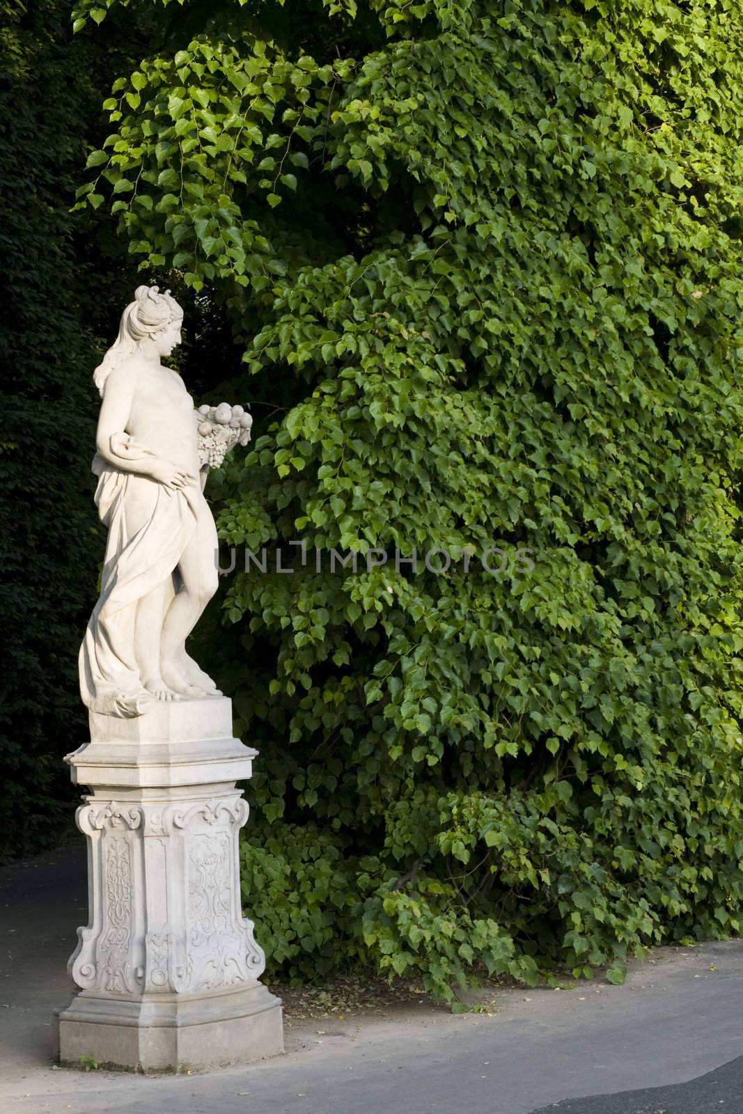 monument of a woman on a green leafes wall background