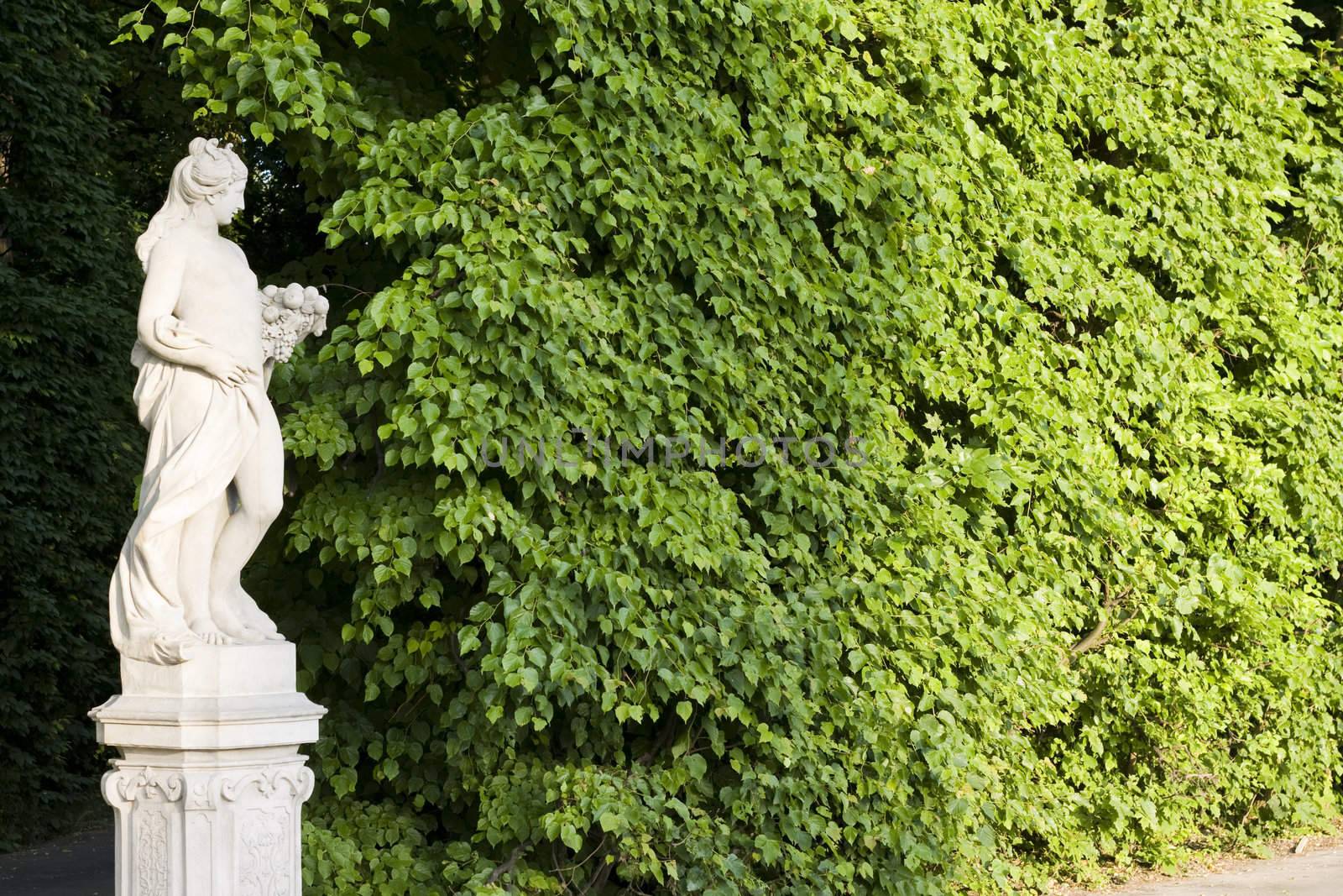 monument of a woman on a green leafes wall background
