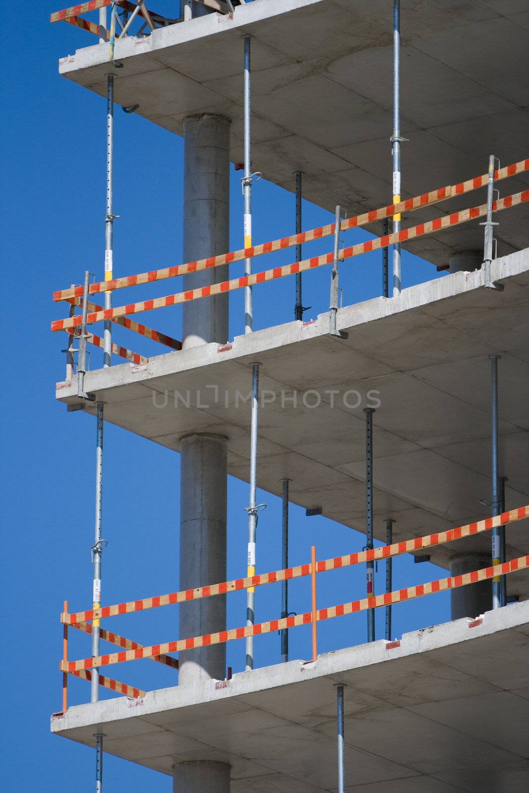 Part of unfinished building with caution marks and concrete walls