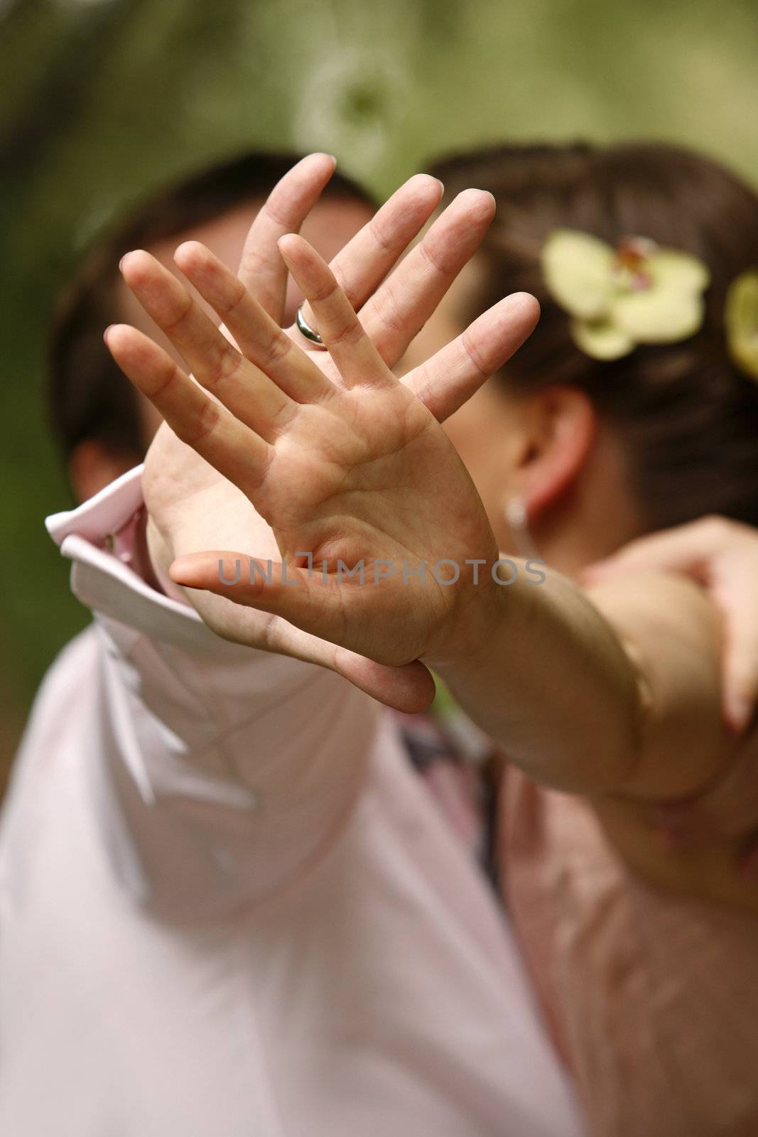 The groom and bride is closed from the photographer by a hand