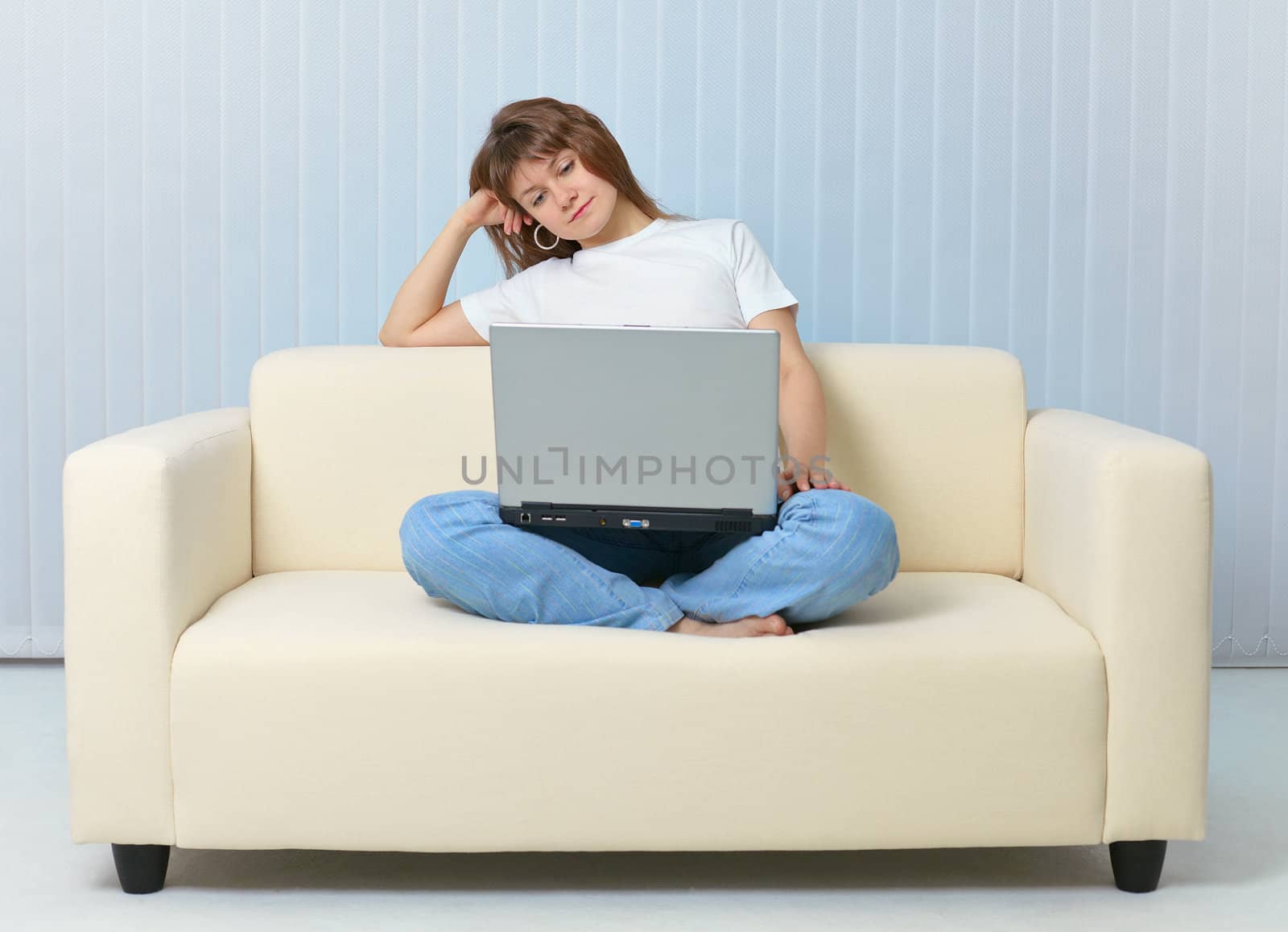 Tired after work woman reads with a laptop on sofa