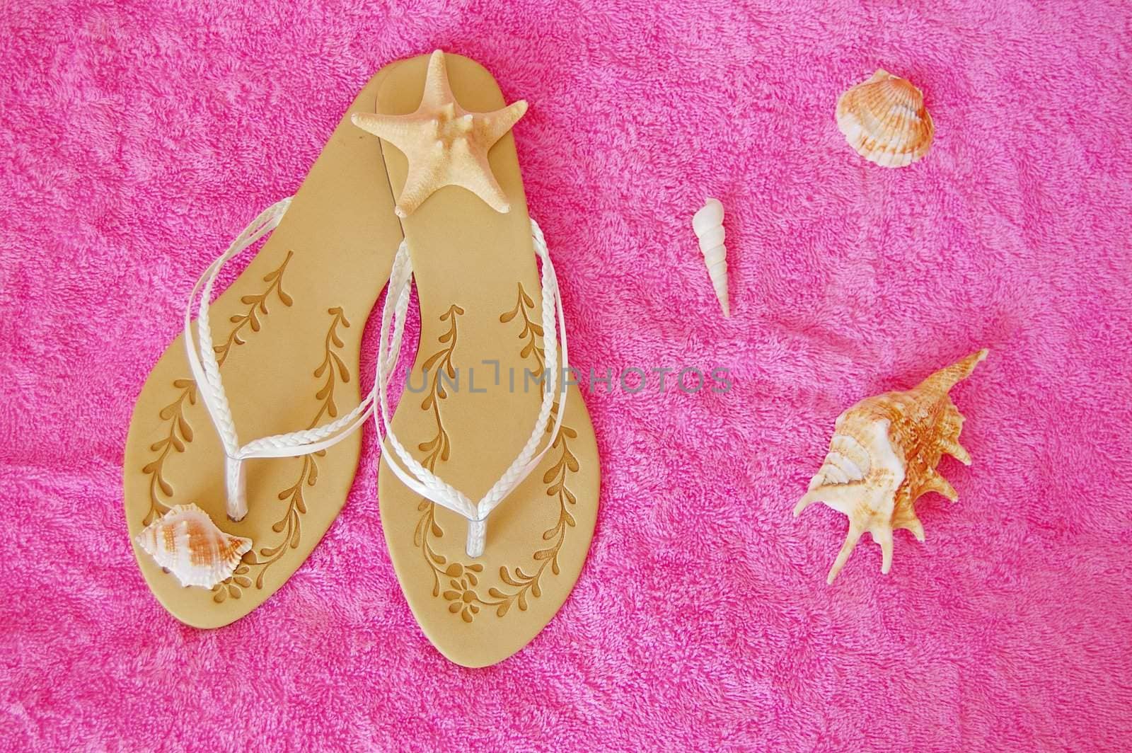 beach sandals with seashells on pink towel