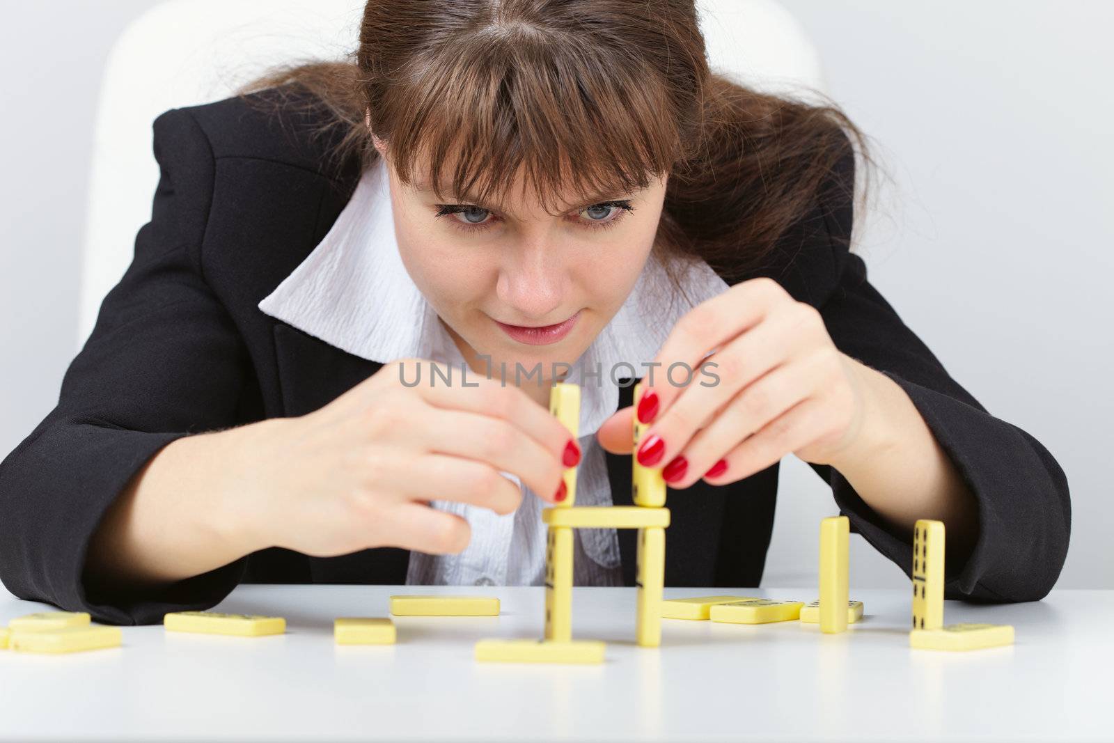 Young woman are concentrated in building a tower on the table with the domino