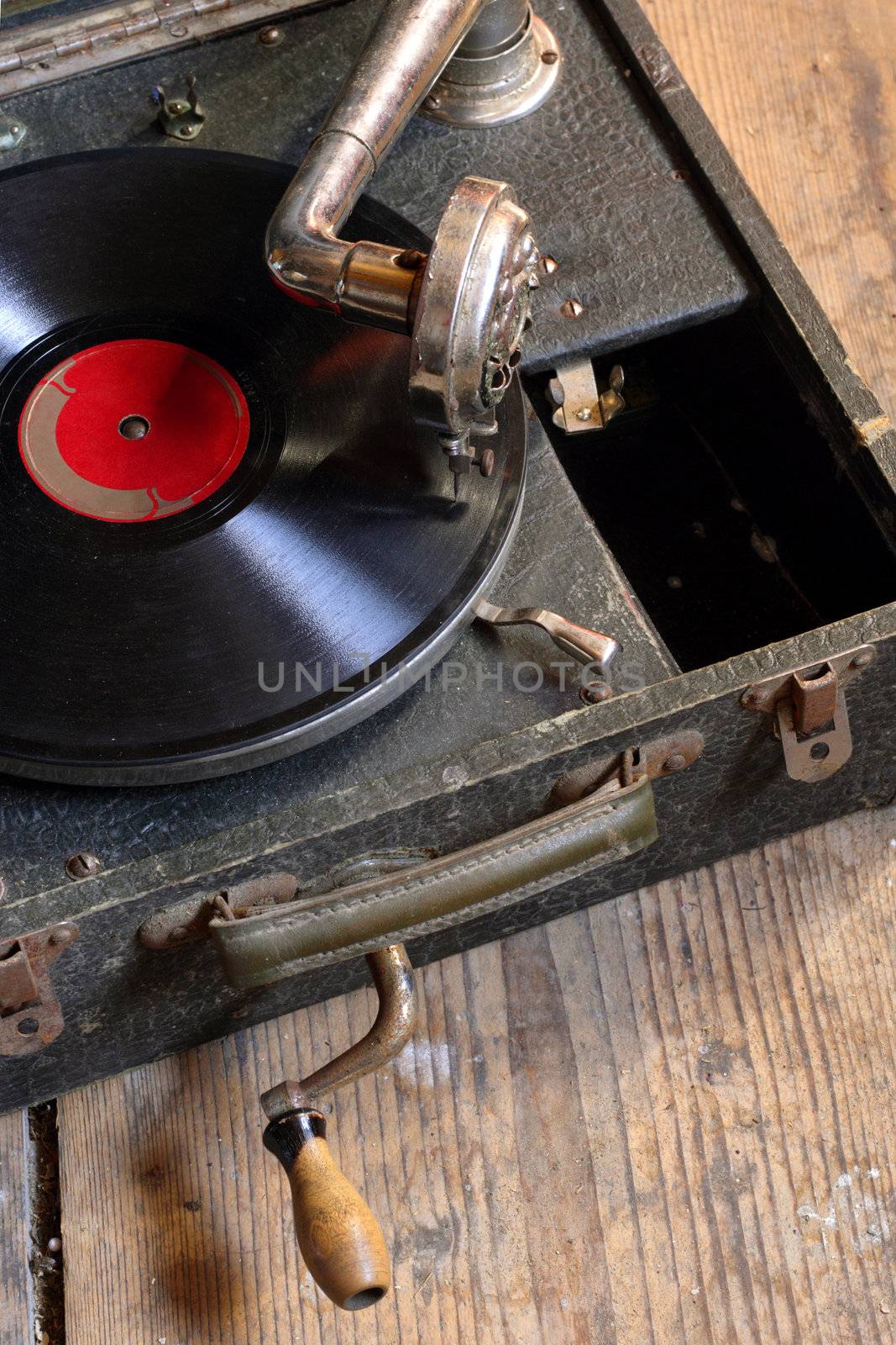 An antique box record player with crank, sitting on the attic floor.
