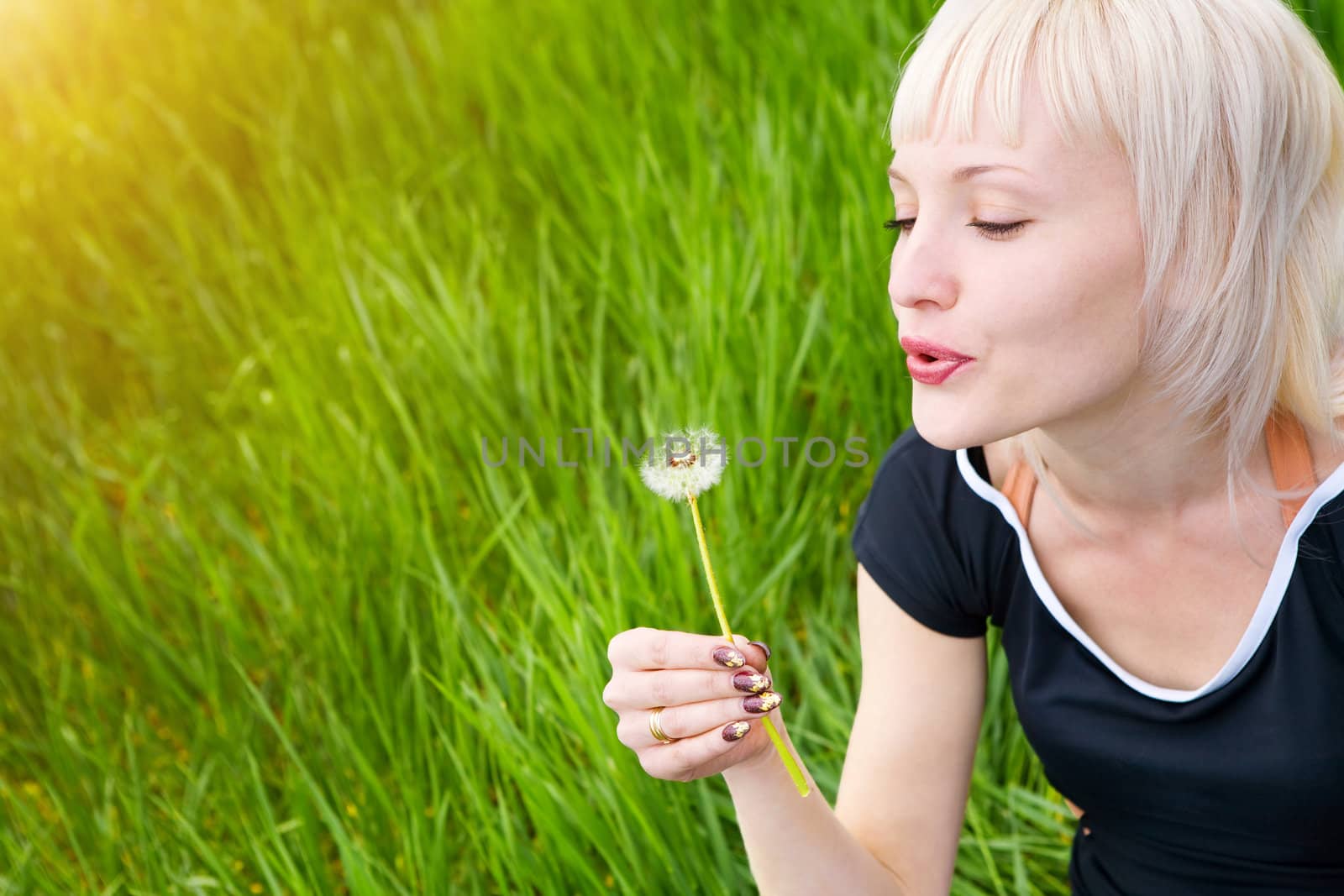blond pretty girl blowing on the dandelion