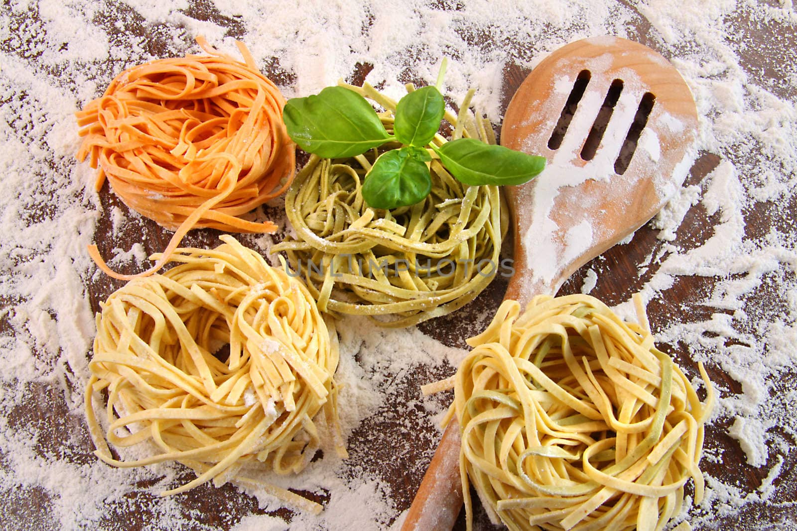 Uncooked italian pasta in three colours with flour