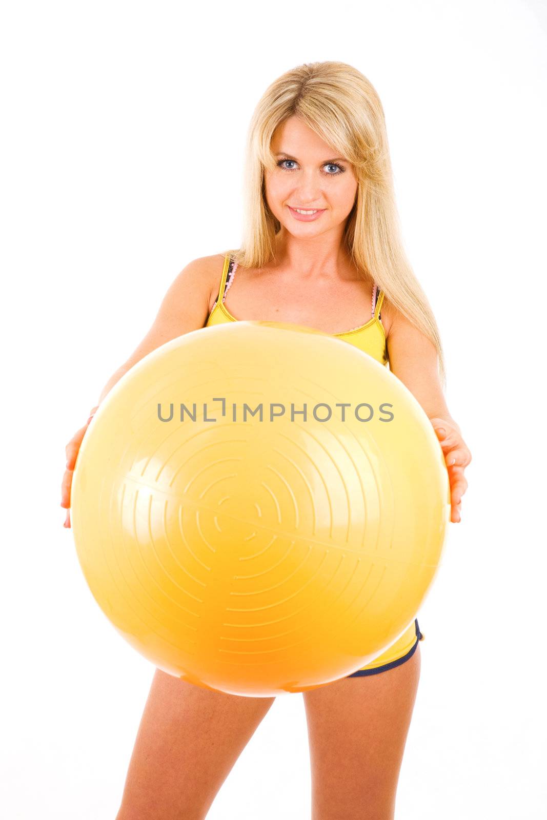 young woman with a big yellow ball in her hands goes in for fitness