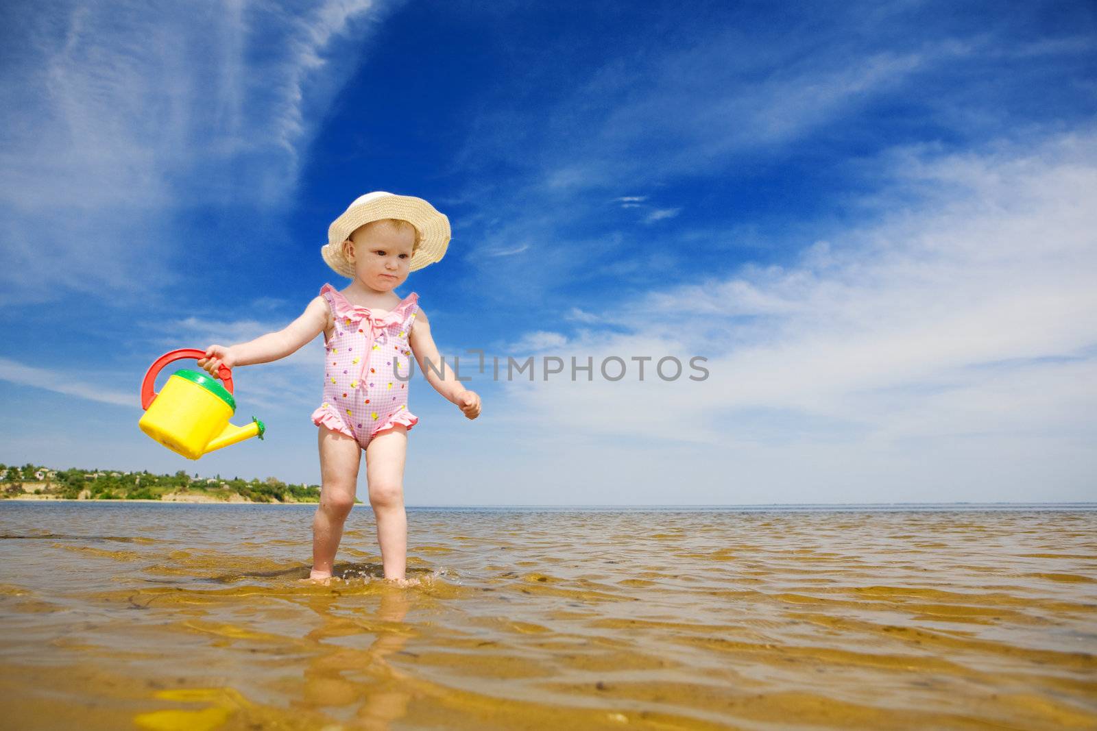 small girl with watering-pot on the seashore