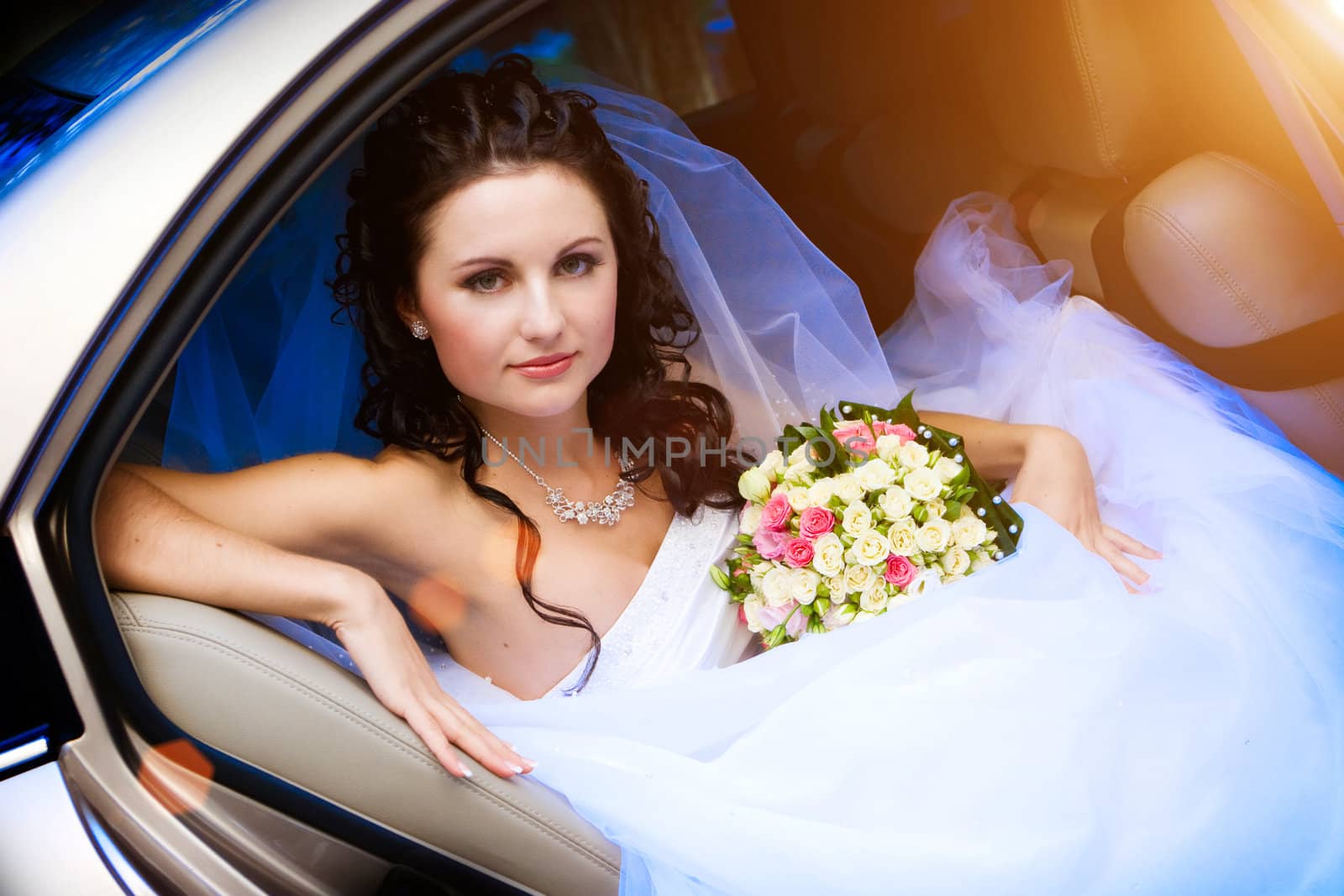 beautiful bride with flowers in the car