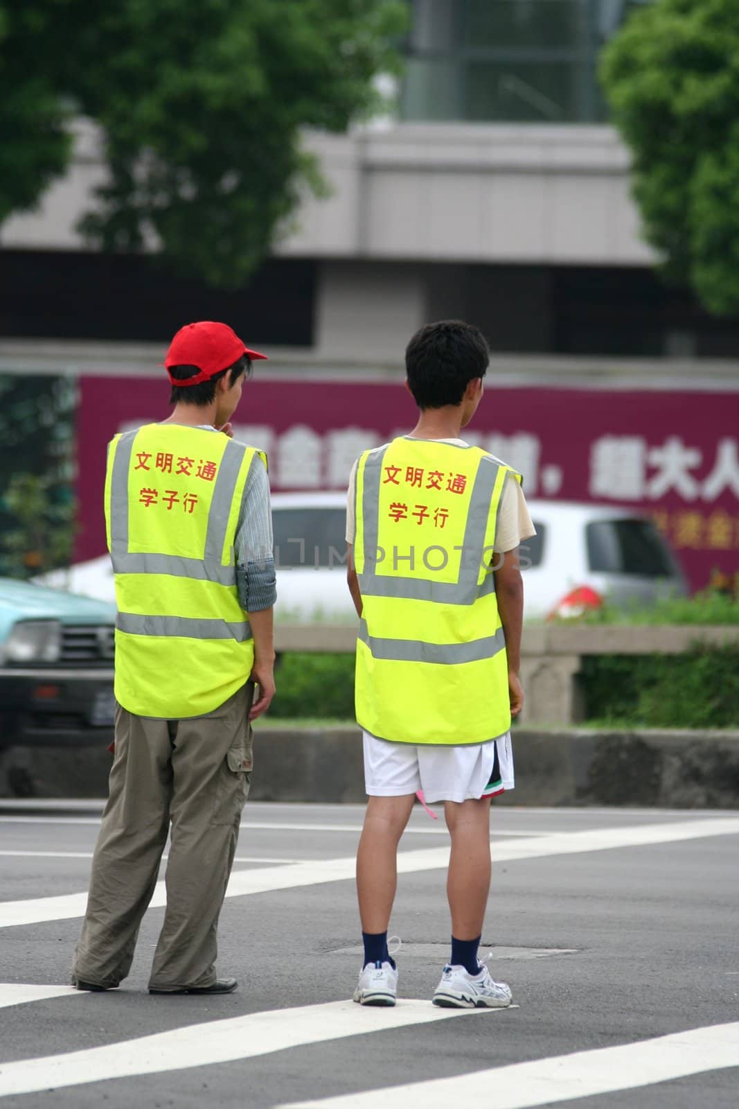 Two chinese teenagers helping pedestrians to cross the road