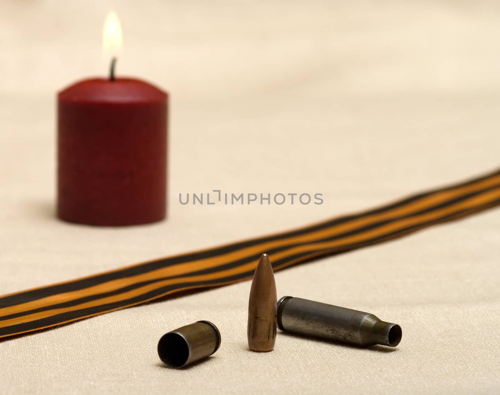 Burning candle, shell, bullet and St. George ribbon closeup.