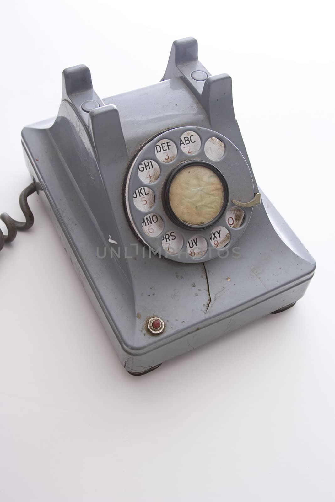 dirty vintage gray unhooked rotary phone with crack casing and expose wired