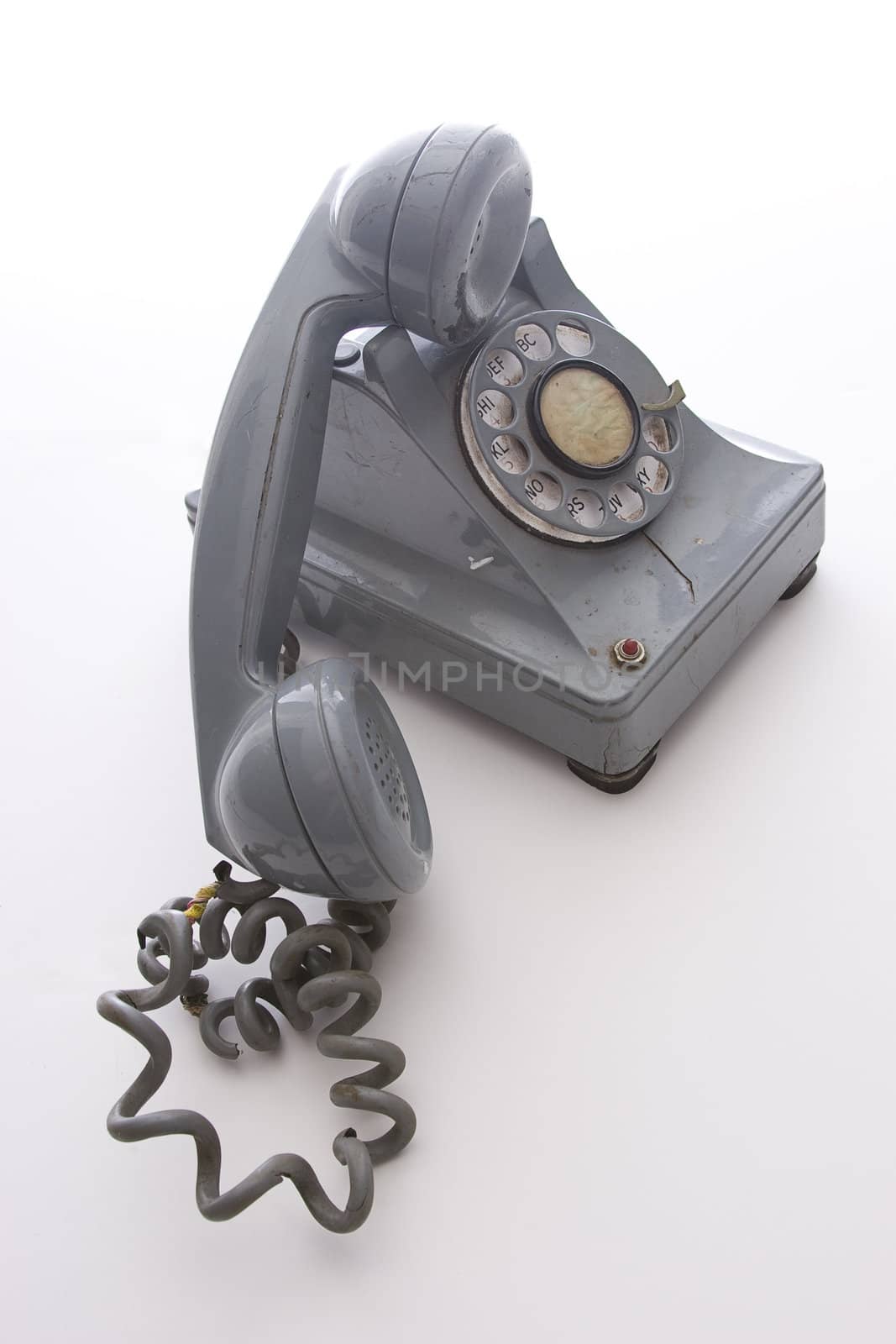 dirty vintage gray unhooked rotary phone with crack casing and expose wired