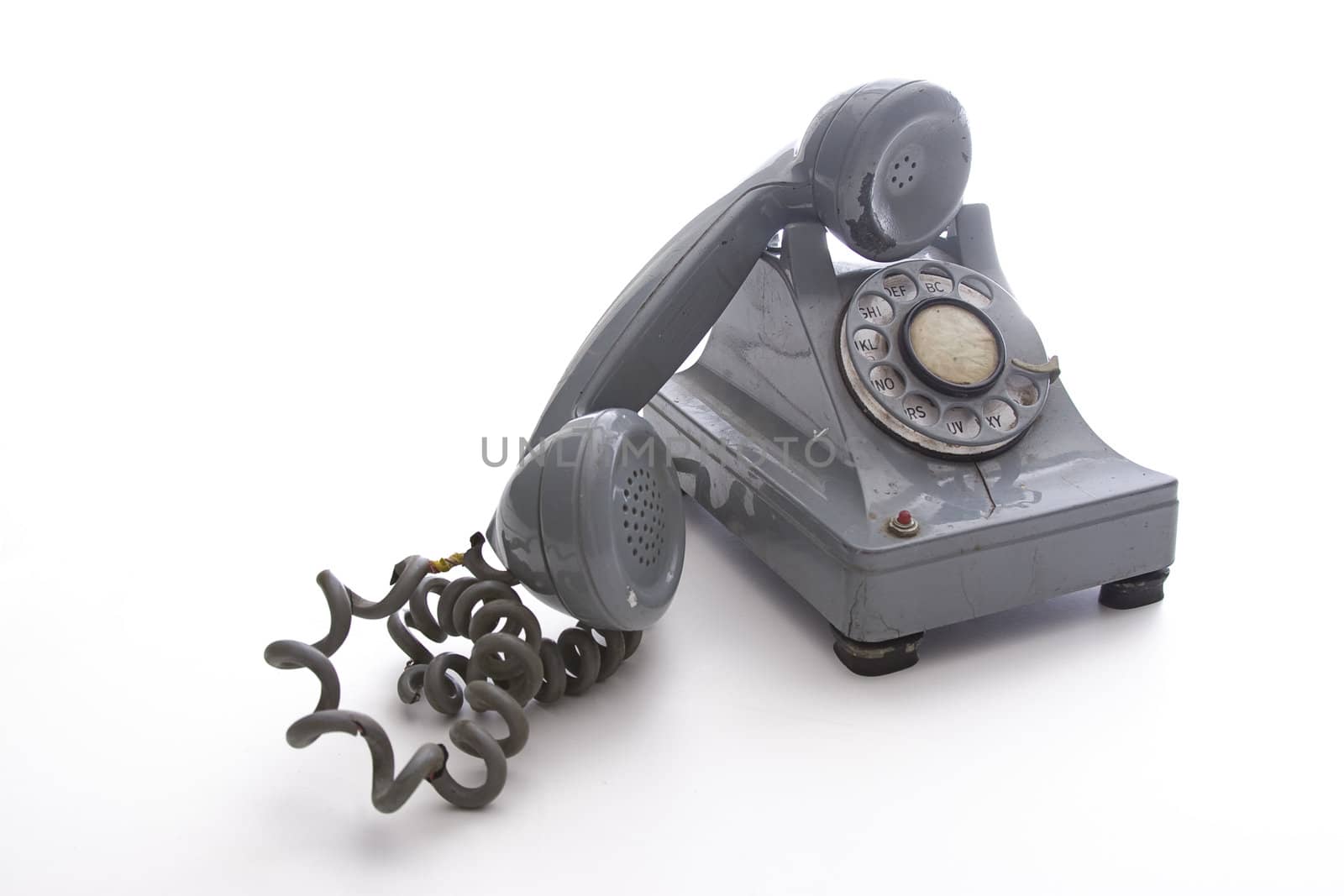 dirty vintage gray unhooked rotary phone with crack casing and expose wired