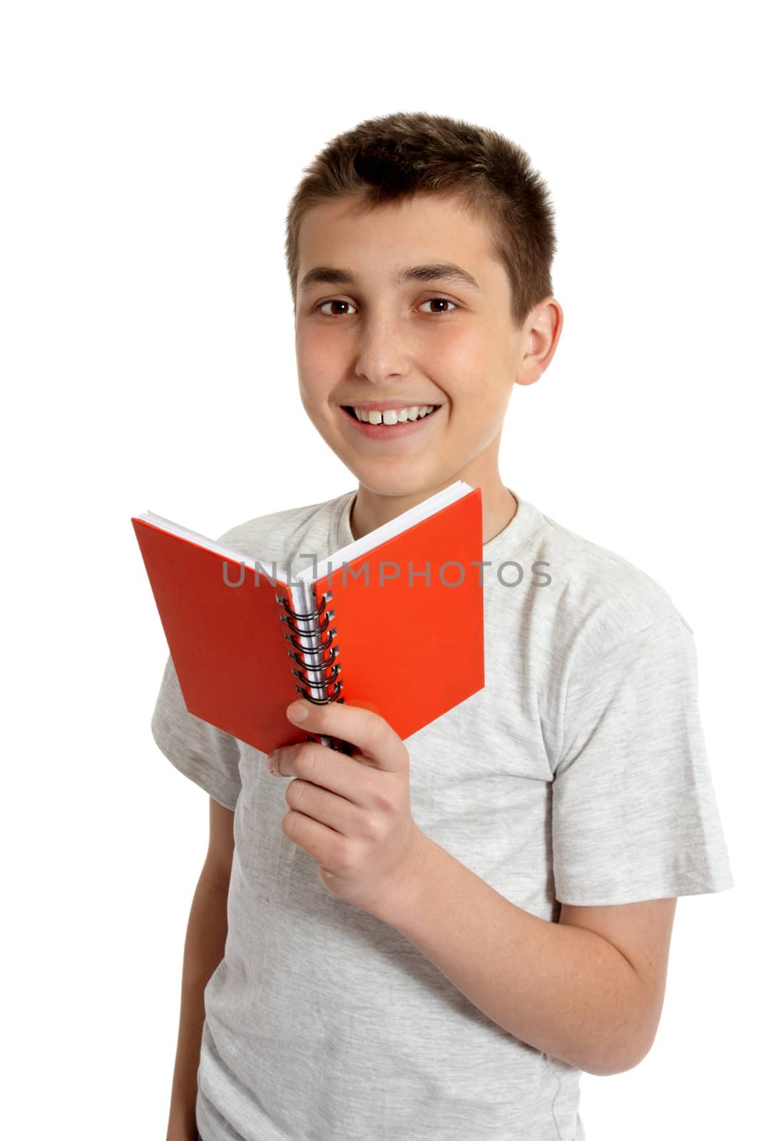 A smiling schoolboy holds an open red book in his hand.