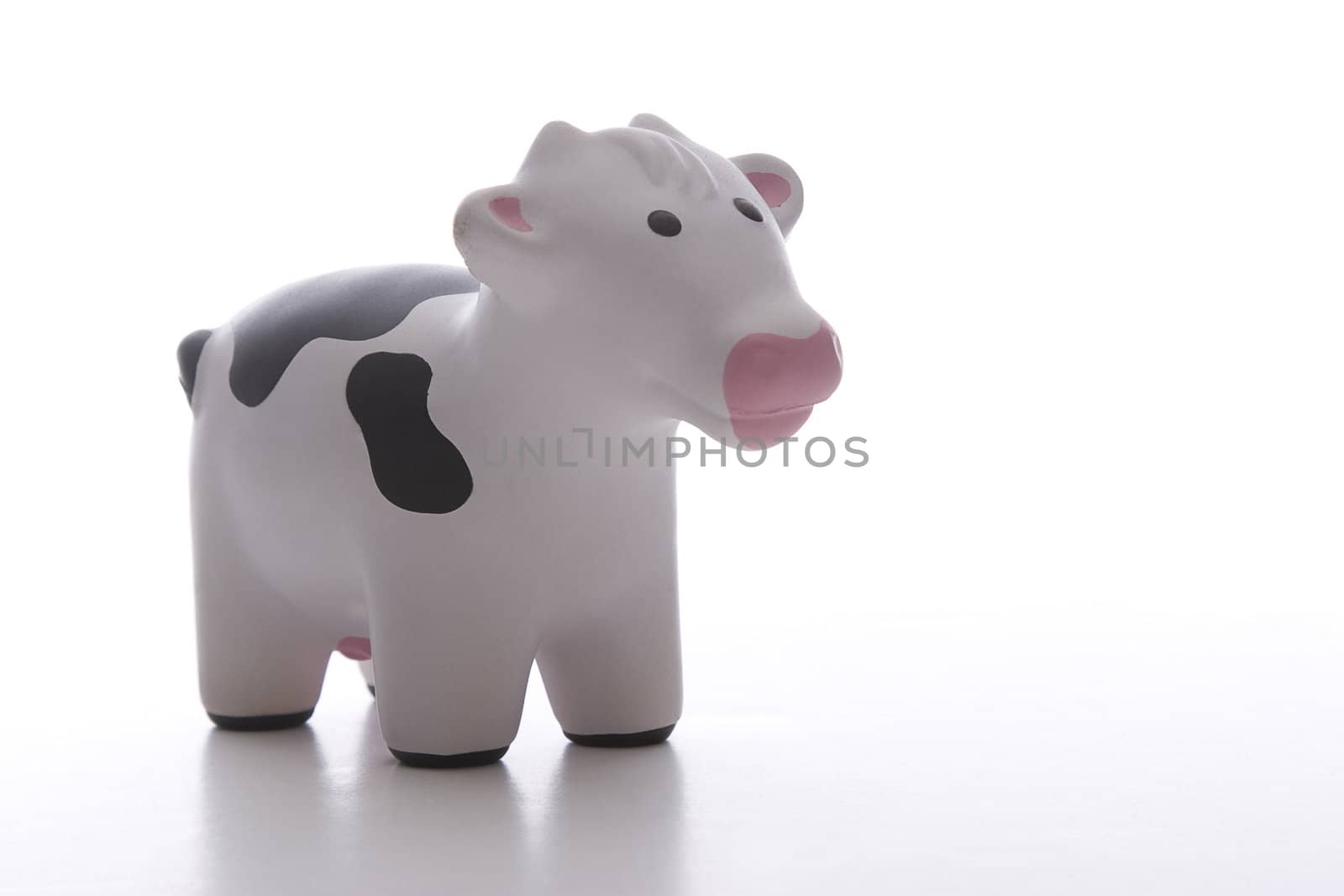 small black and white toy cow against white background