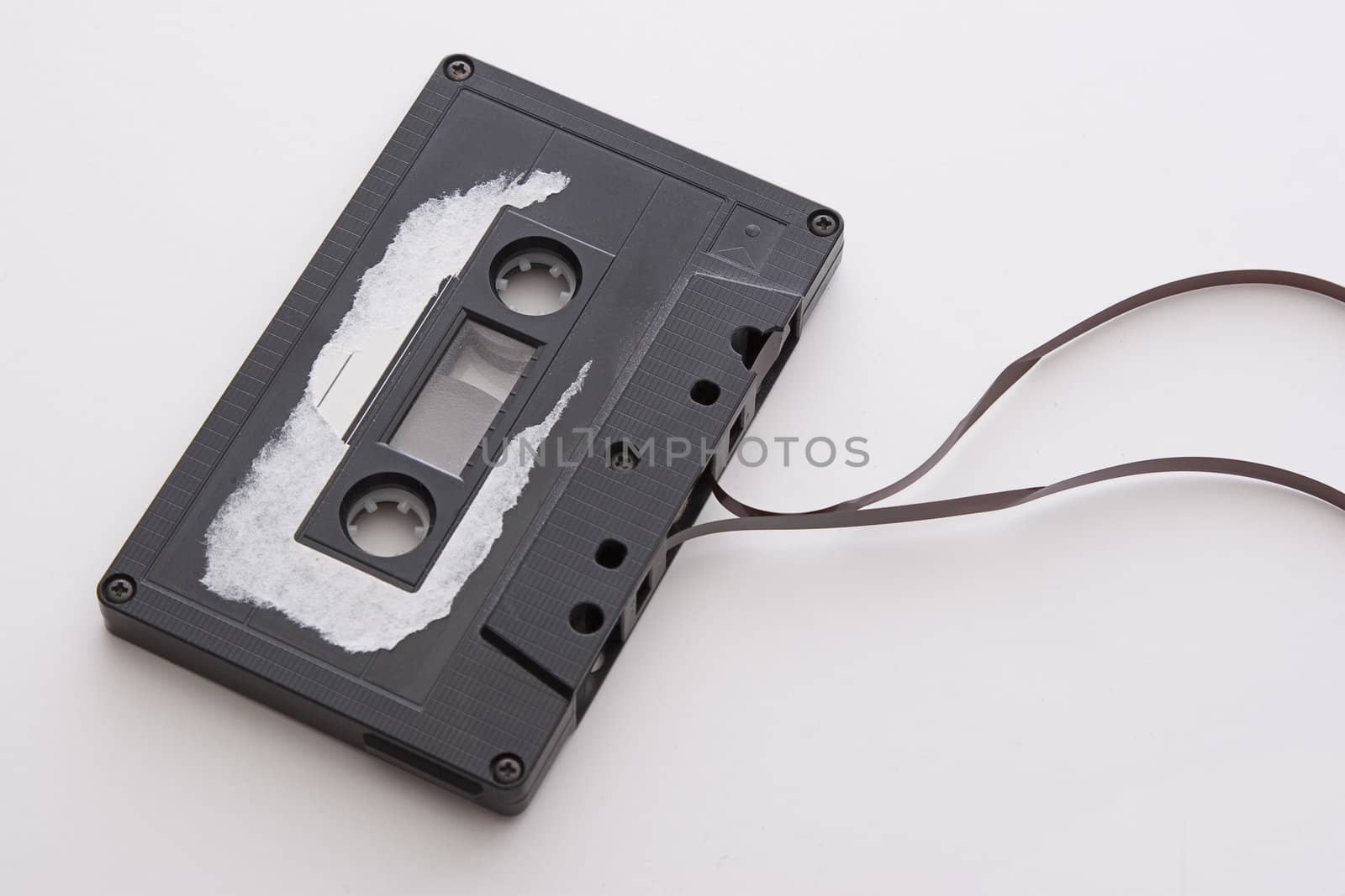 old tape cassette with cover sticker rip apart and part of the tape unrolled