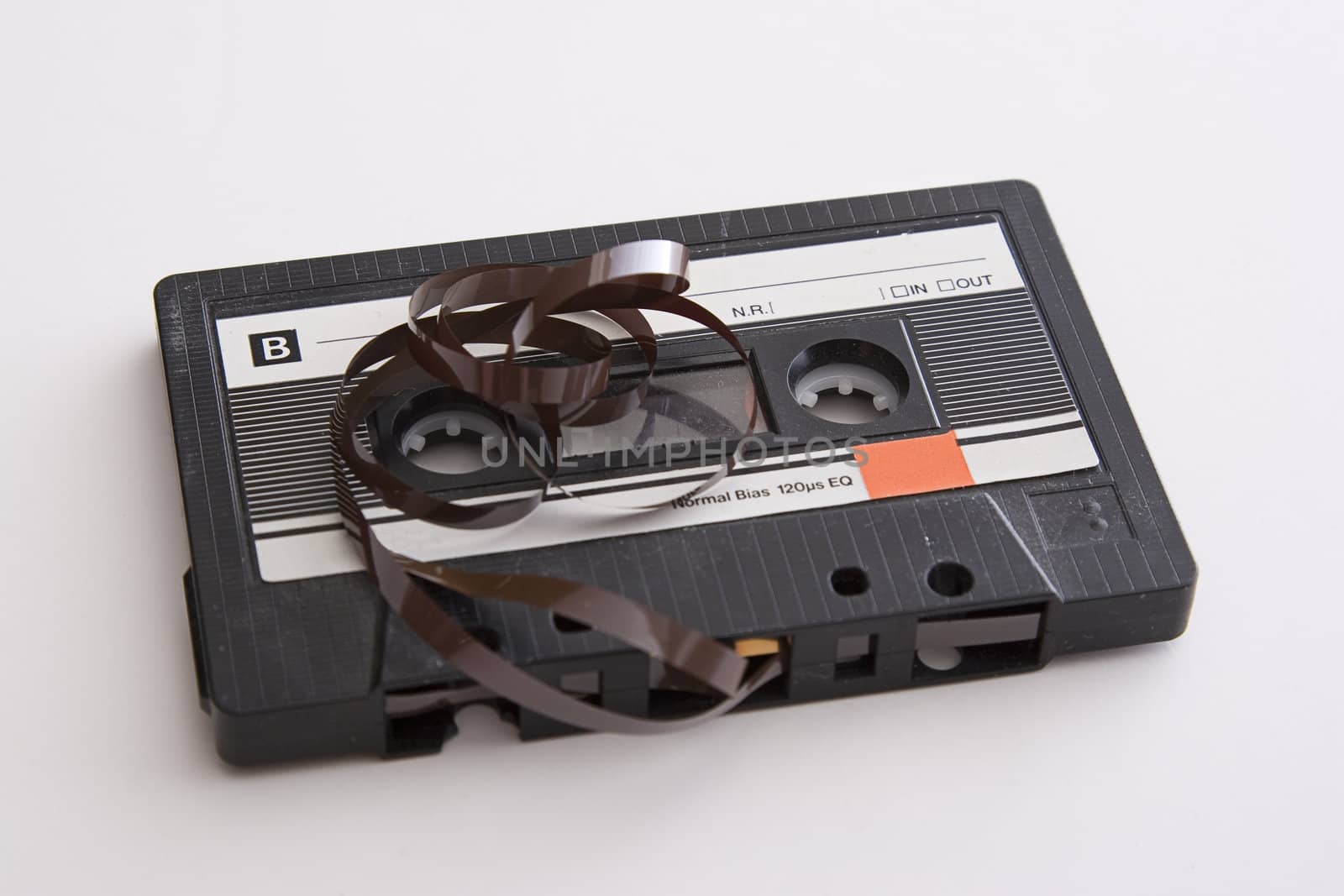 old tape cassette with cover sticker and part of the tape unrolled