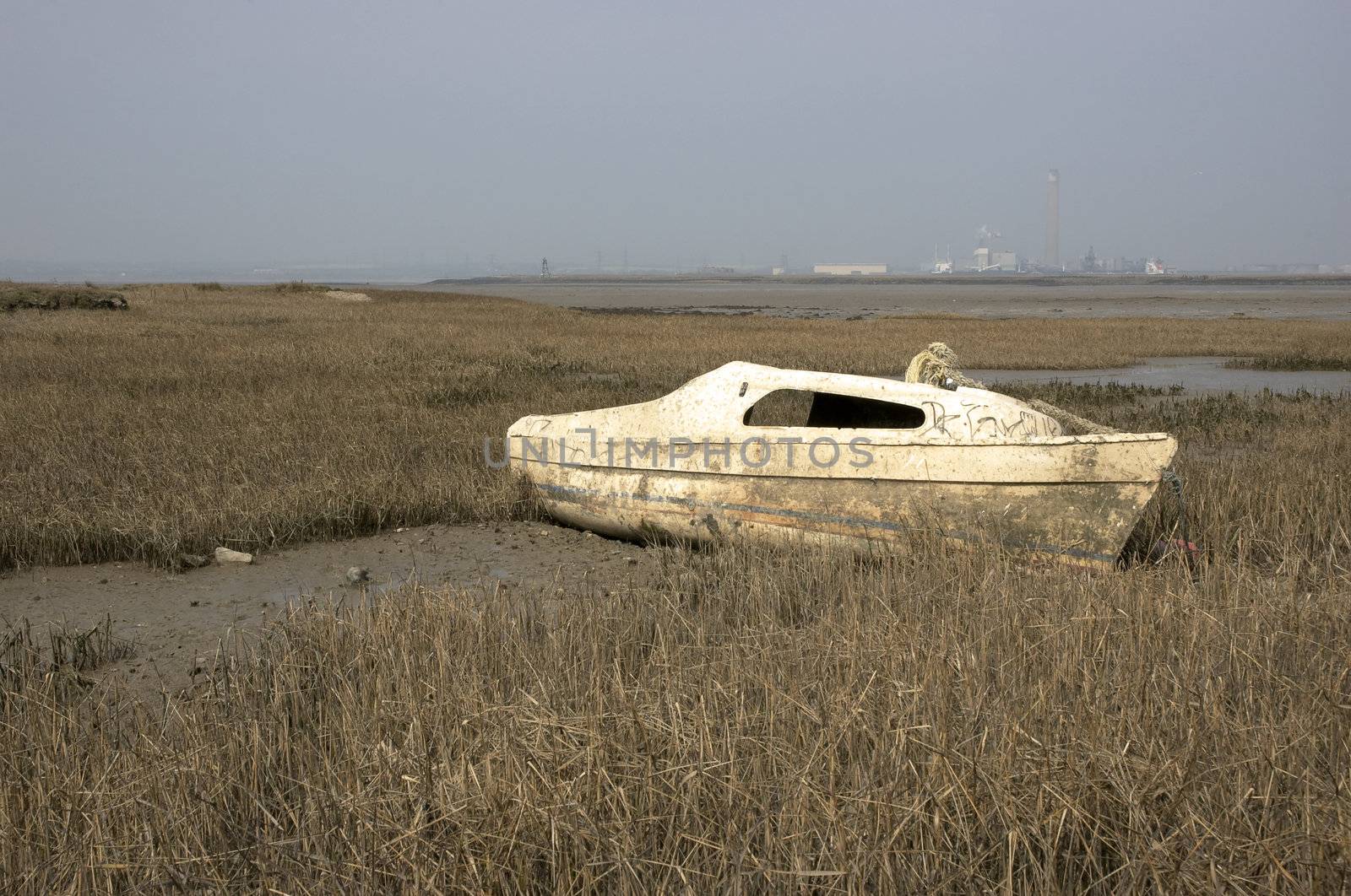 a small boat abandoned in the mud at low tide