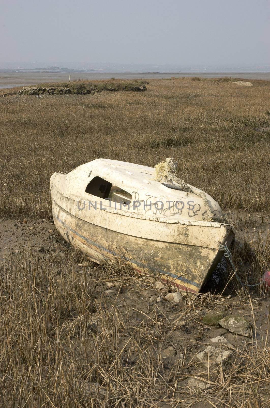a small boat abandoned in the mud at low tide