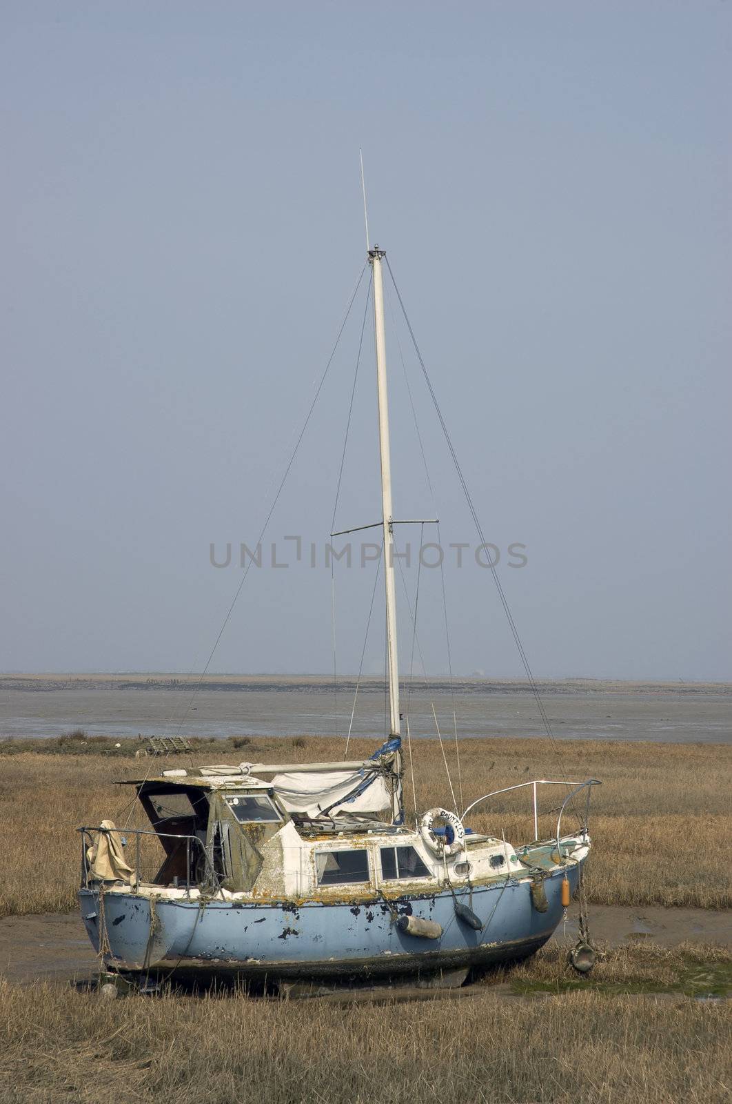 A small yacht in the mud at low tide