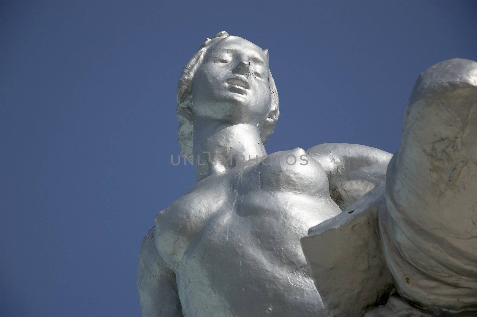 A face silver staue of a nude woman with a clear blue skyl