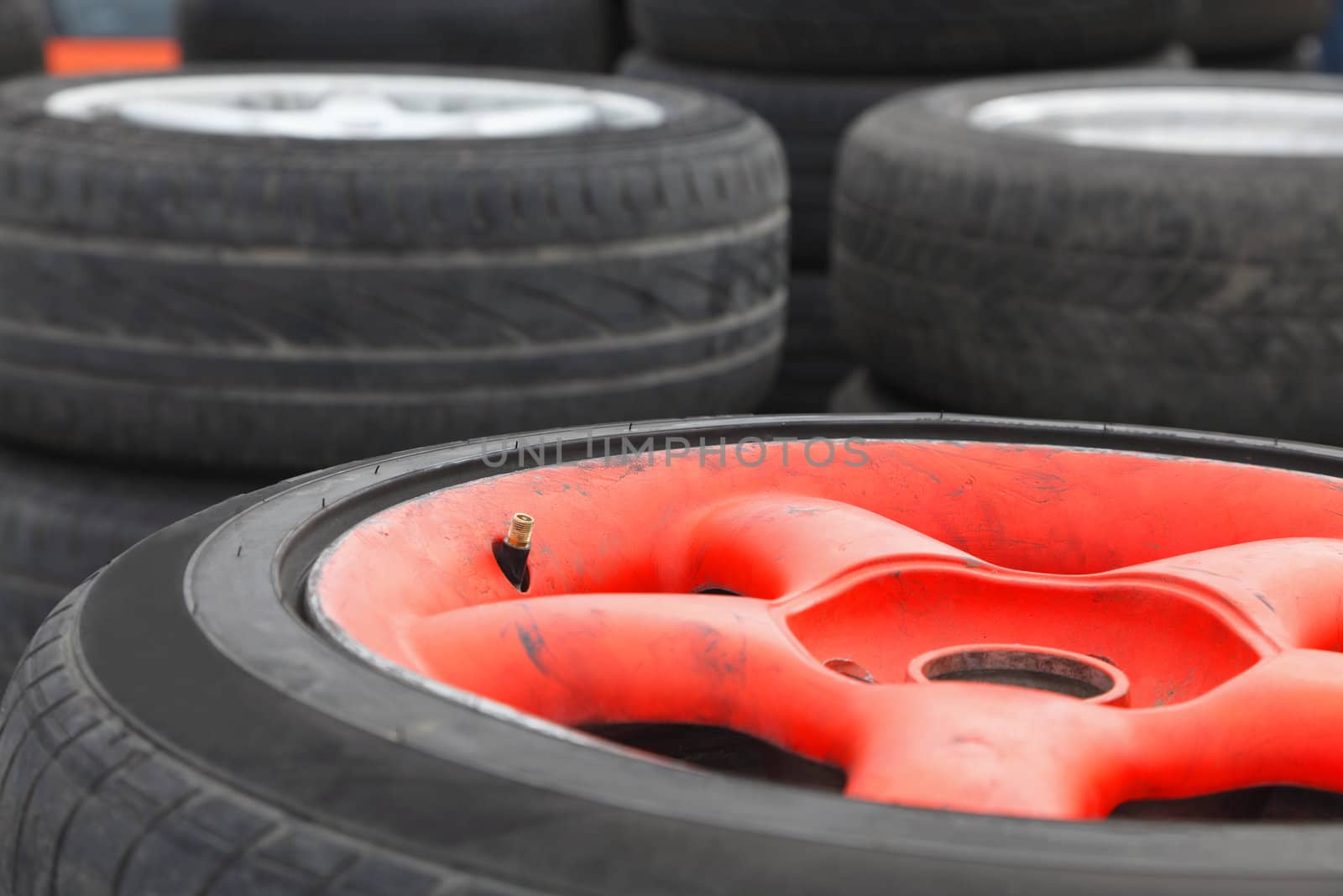 Image of a heap of race car wheels. Slective focus on the tyre valve. 