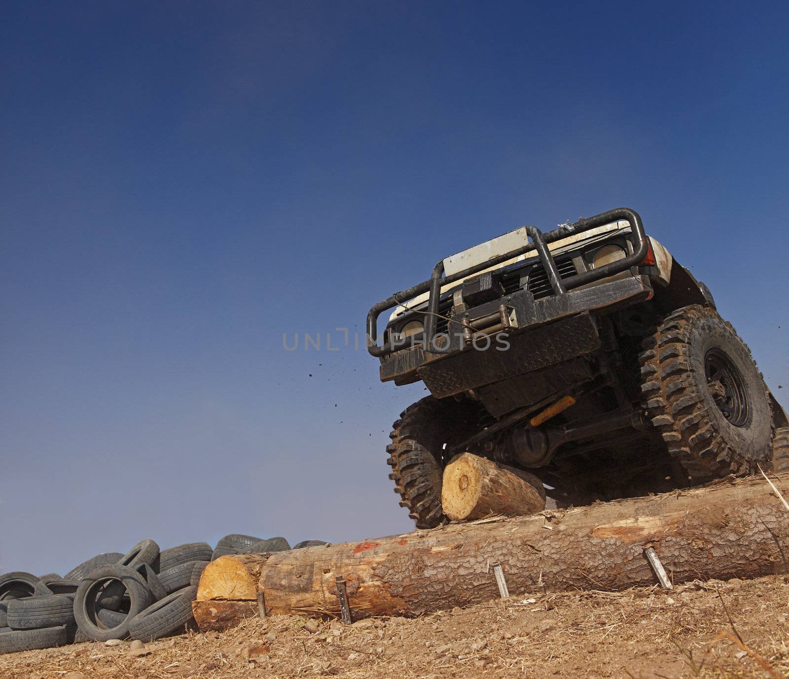 Off road car passing a tree trunk obstacle during a competition.