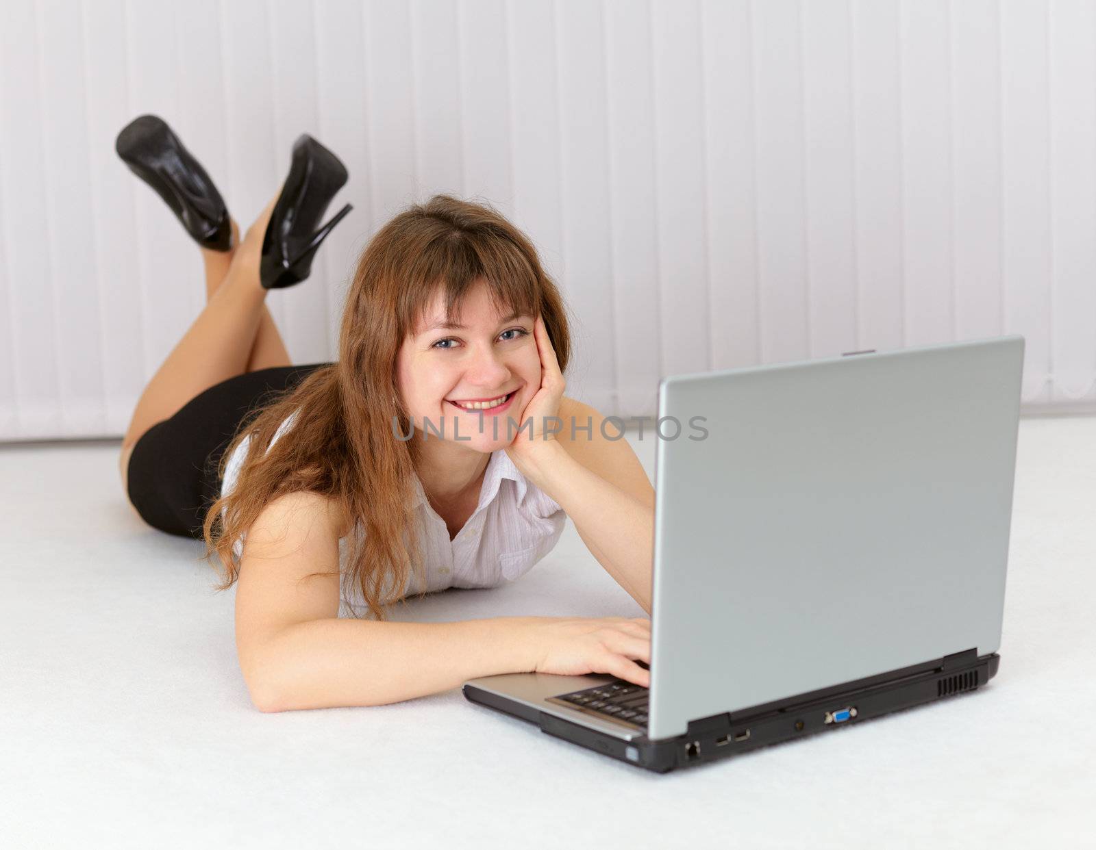 Happy young woman lying on the floor with laptop