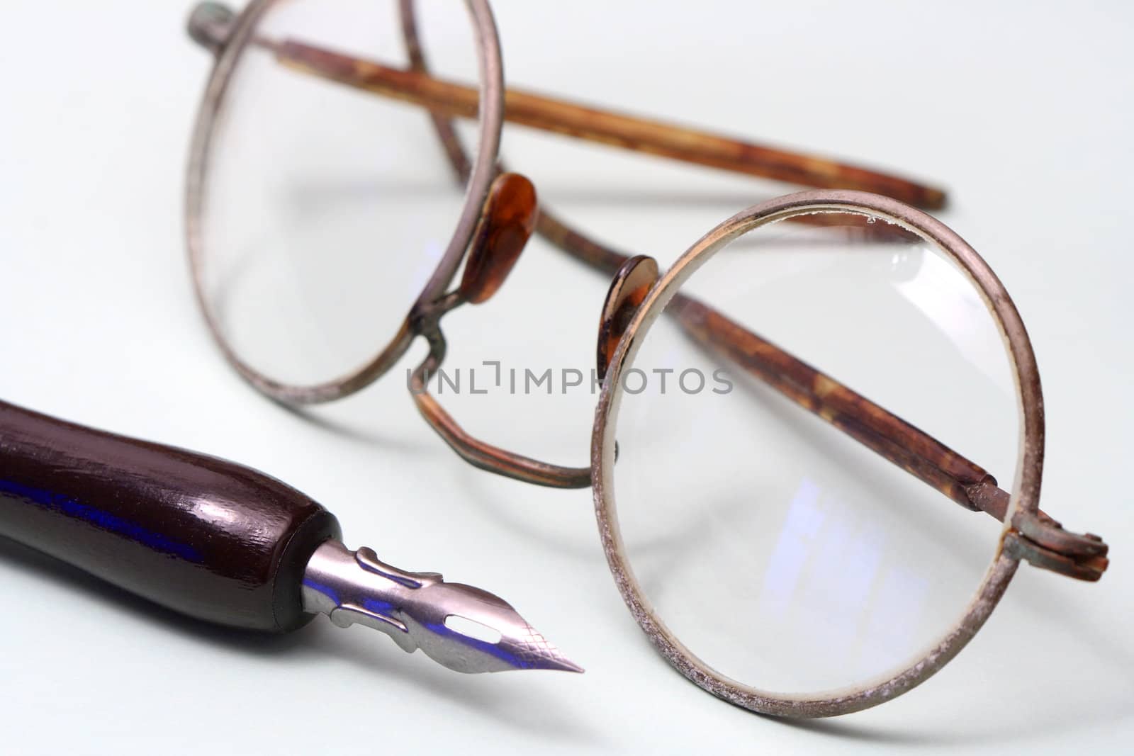 Closeup of old spectacles and fountain pen on gray background