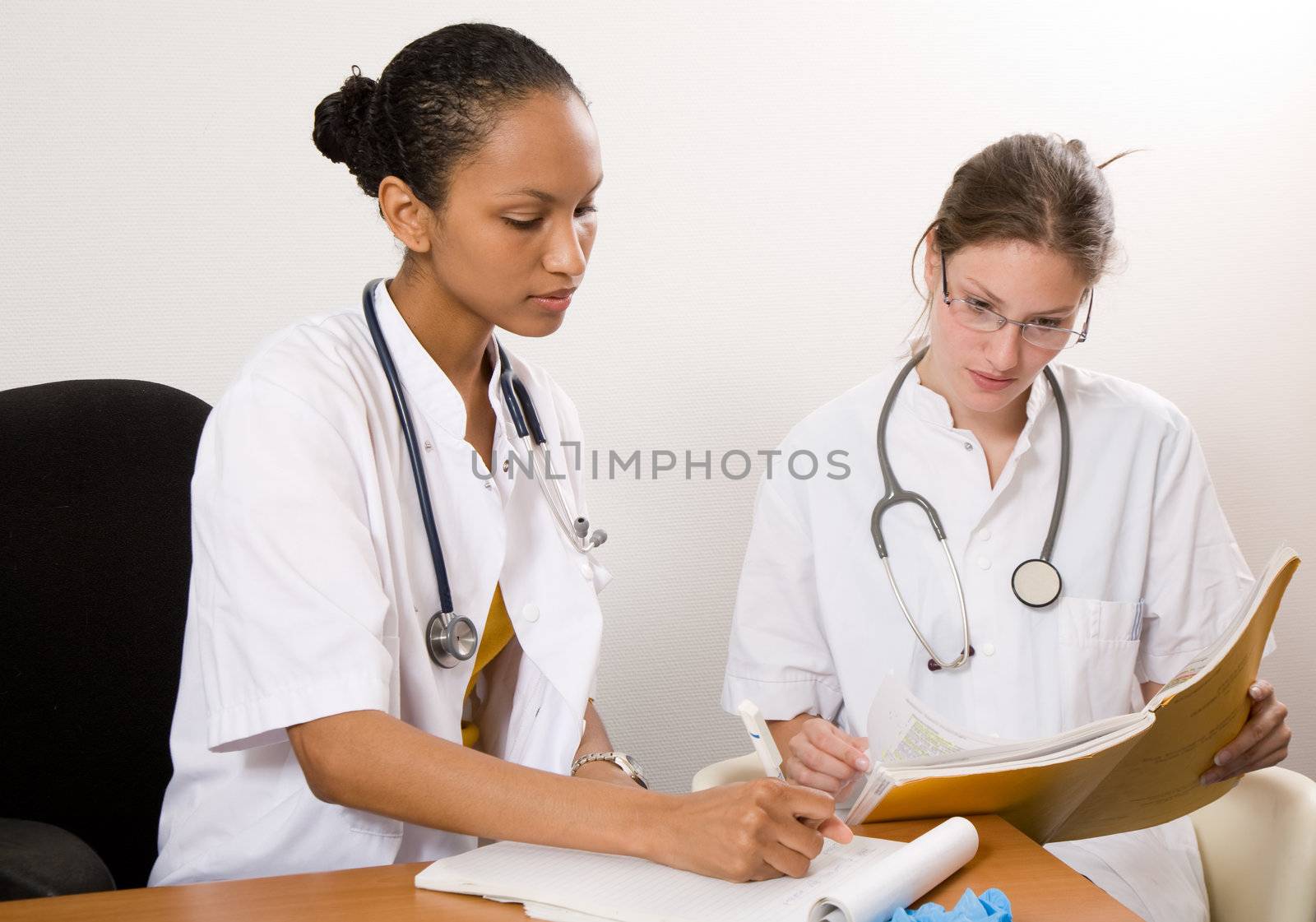 Two young doctors sitting together and discussing a case