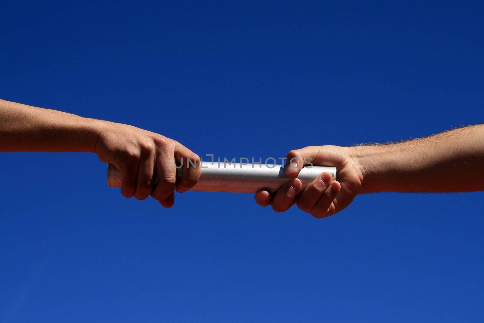 hands passing the batton against blue sky