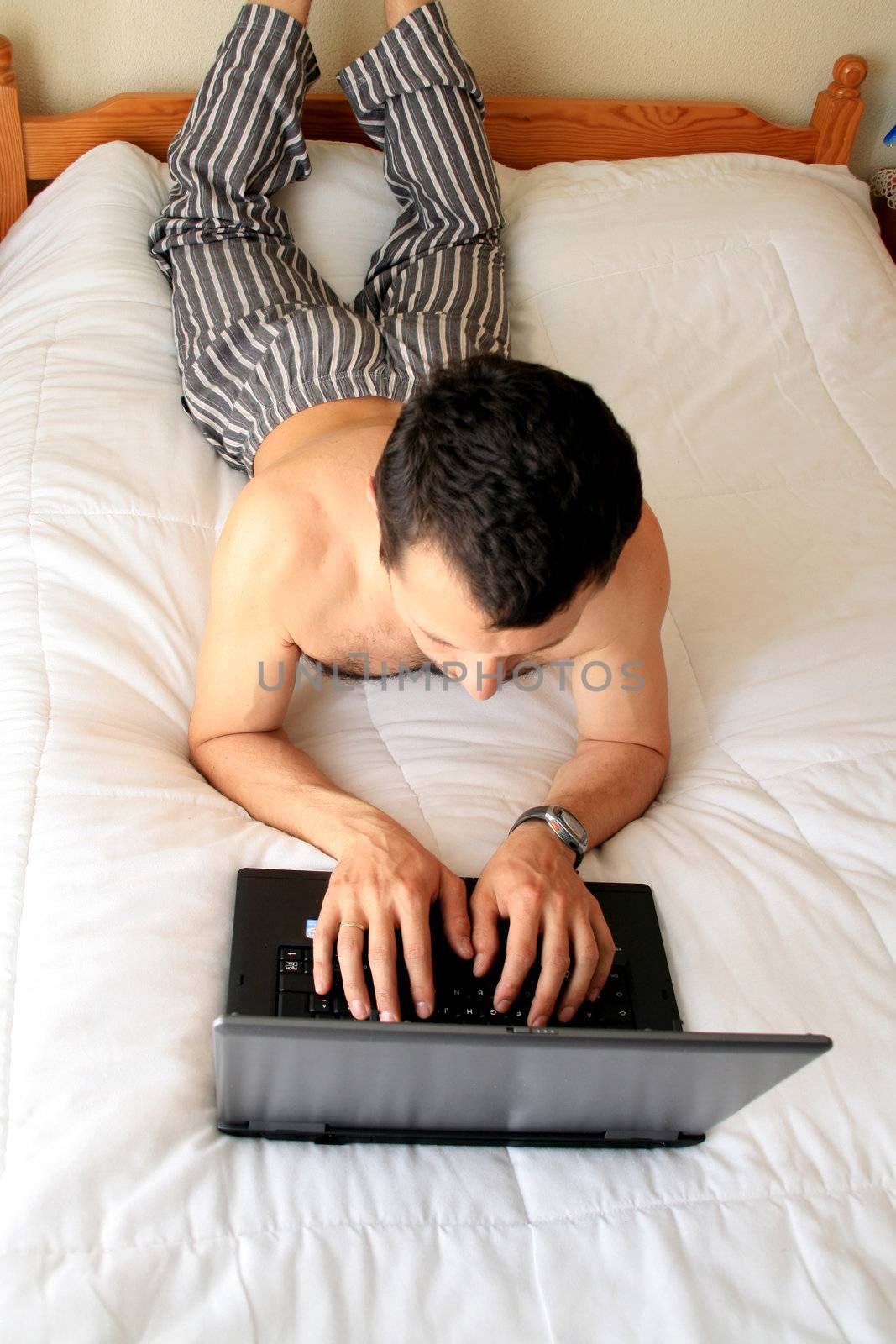 man on working on laptop in bed
