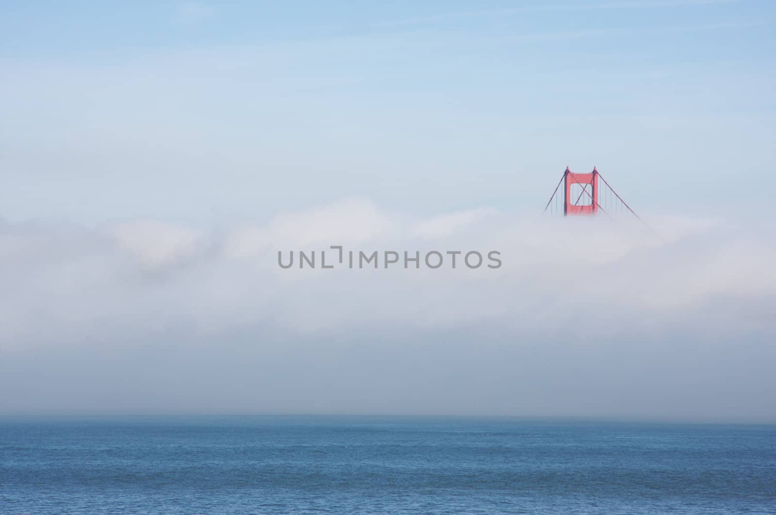 A Golden Gate Bridge tower peaks out of the early morning fog. San Francisco, California, United States.