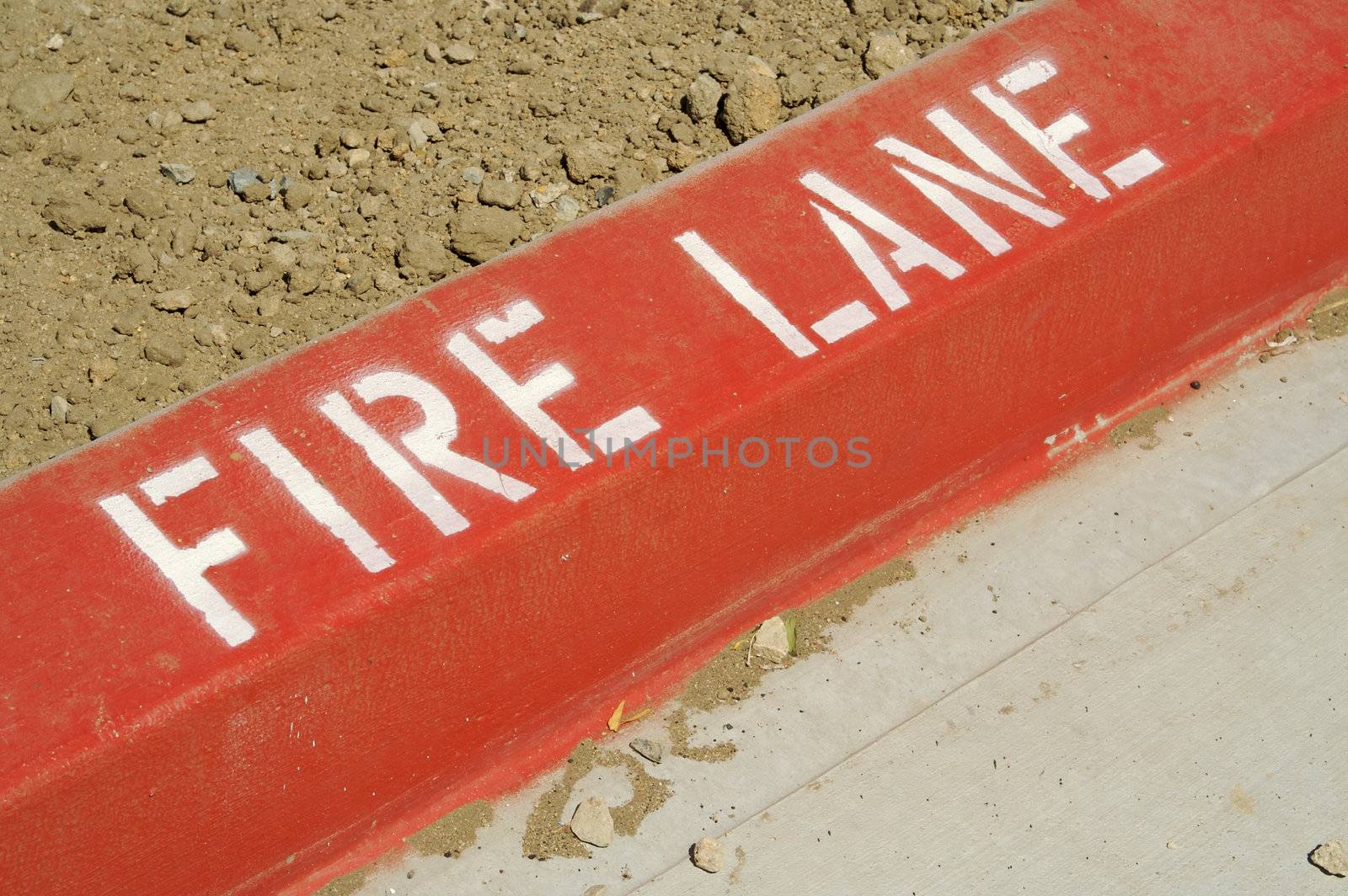 Close-up of red painted curb with Fire Lane text.
