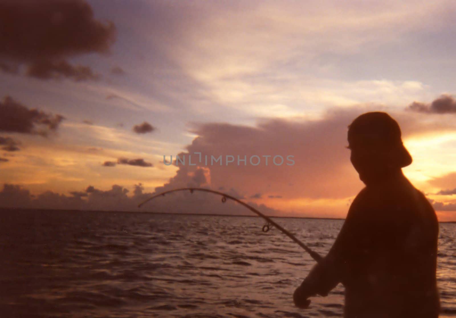 A fisherman silhouetted agains an early morning, or early evening sky