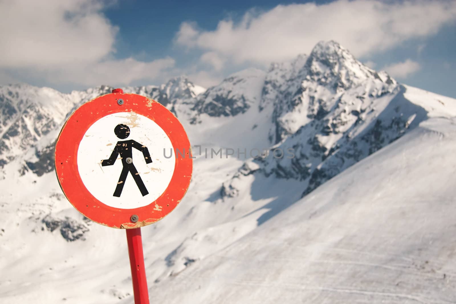 Red and White sign in snow capped mountains.