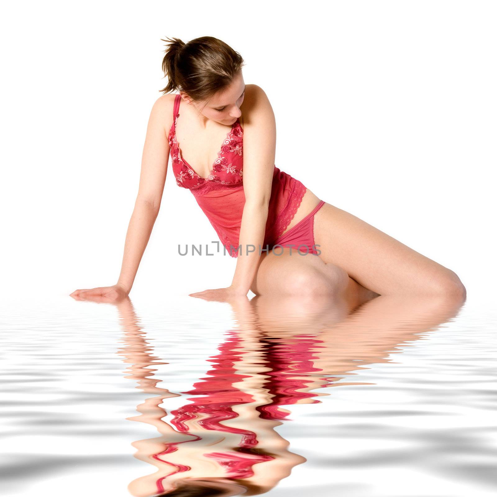 Studio portrait of a young woman in red lingerie sitting by water