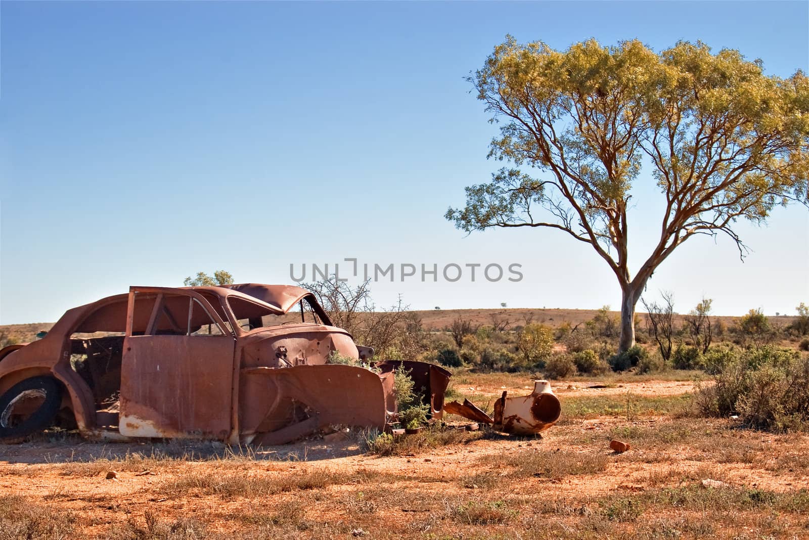 an old car lays rusting in the desert