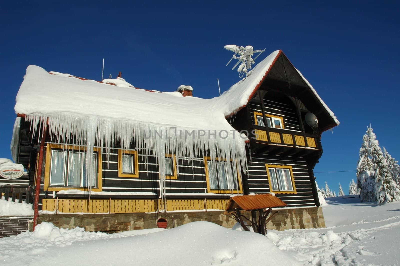 czech snowy tourist cottage with icicle and blue sky