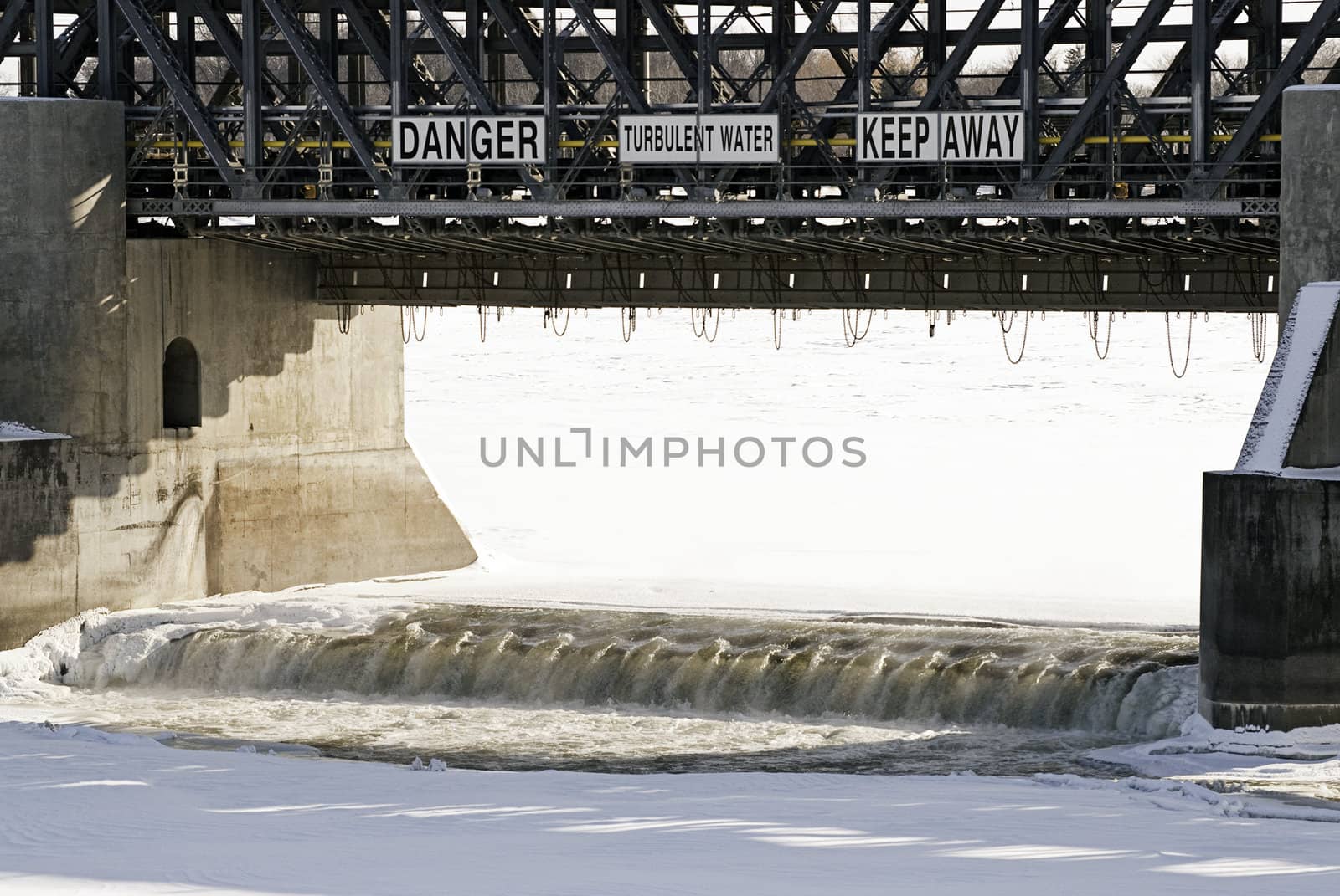 Close-up view of a open dam in the winter with dangerous and turbulent waters.