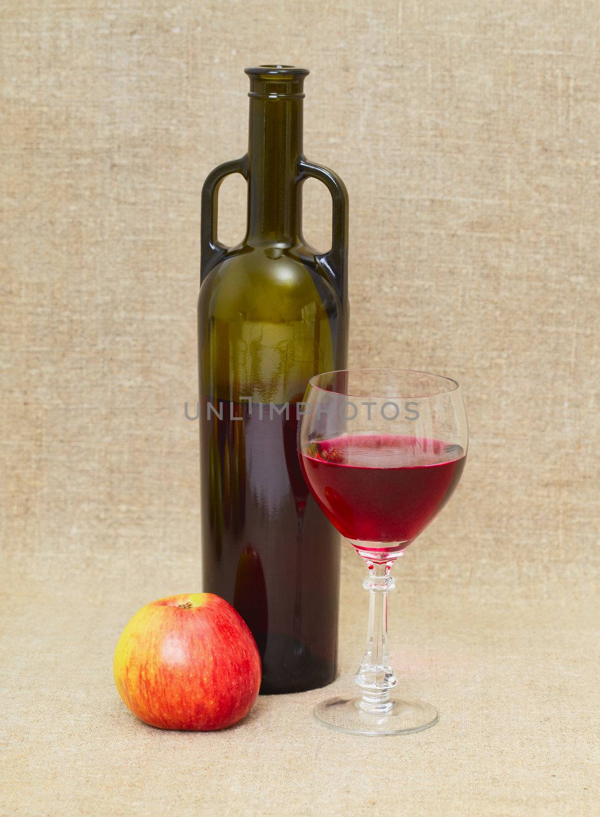 Still life with green bottle, apple and glass on canvas background
